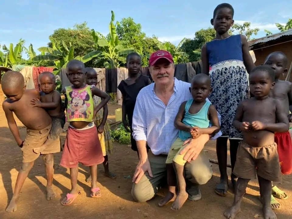 Bill Wegener kneeling with a group of children in a Ugandan village.