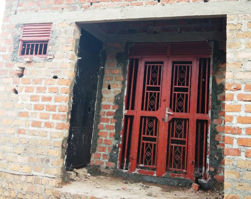 Red metal door and window frame installed on the brick house still under construction.