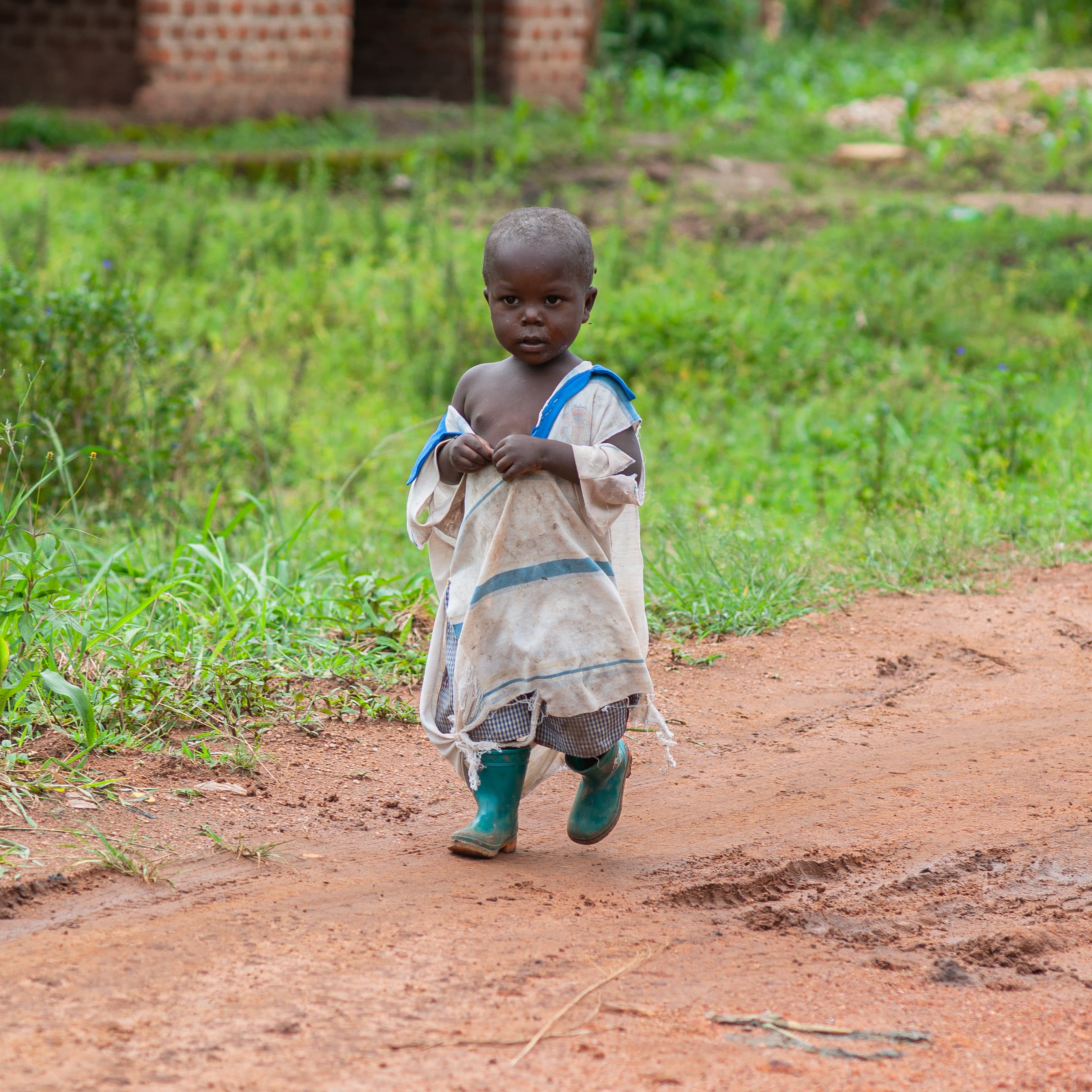 A toddler walks alone along a dirt path.