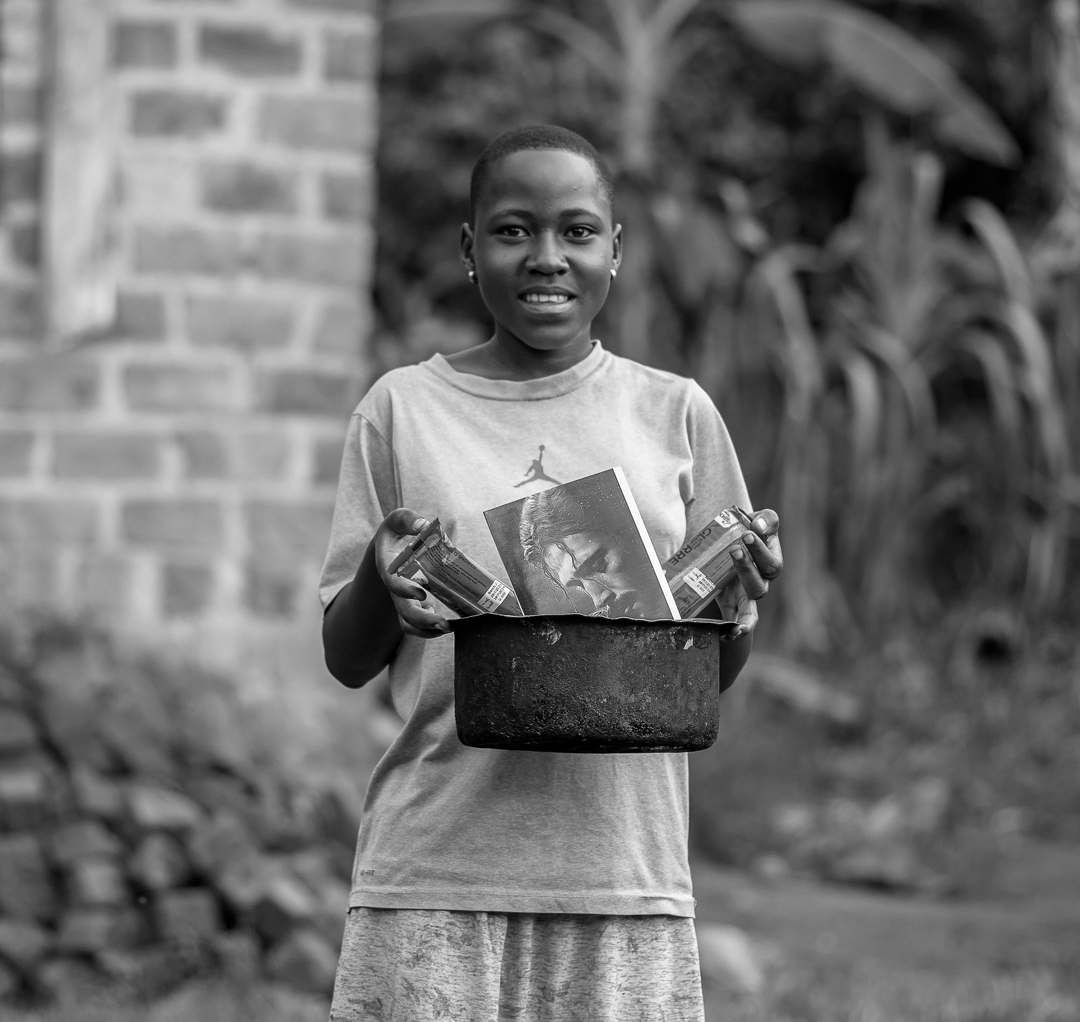 Black-and-white photo of a woman holding a pot filled with food gift items.