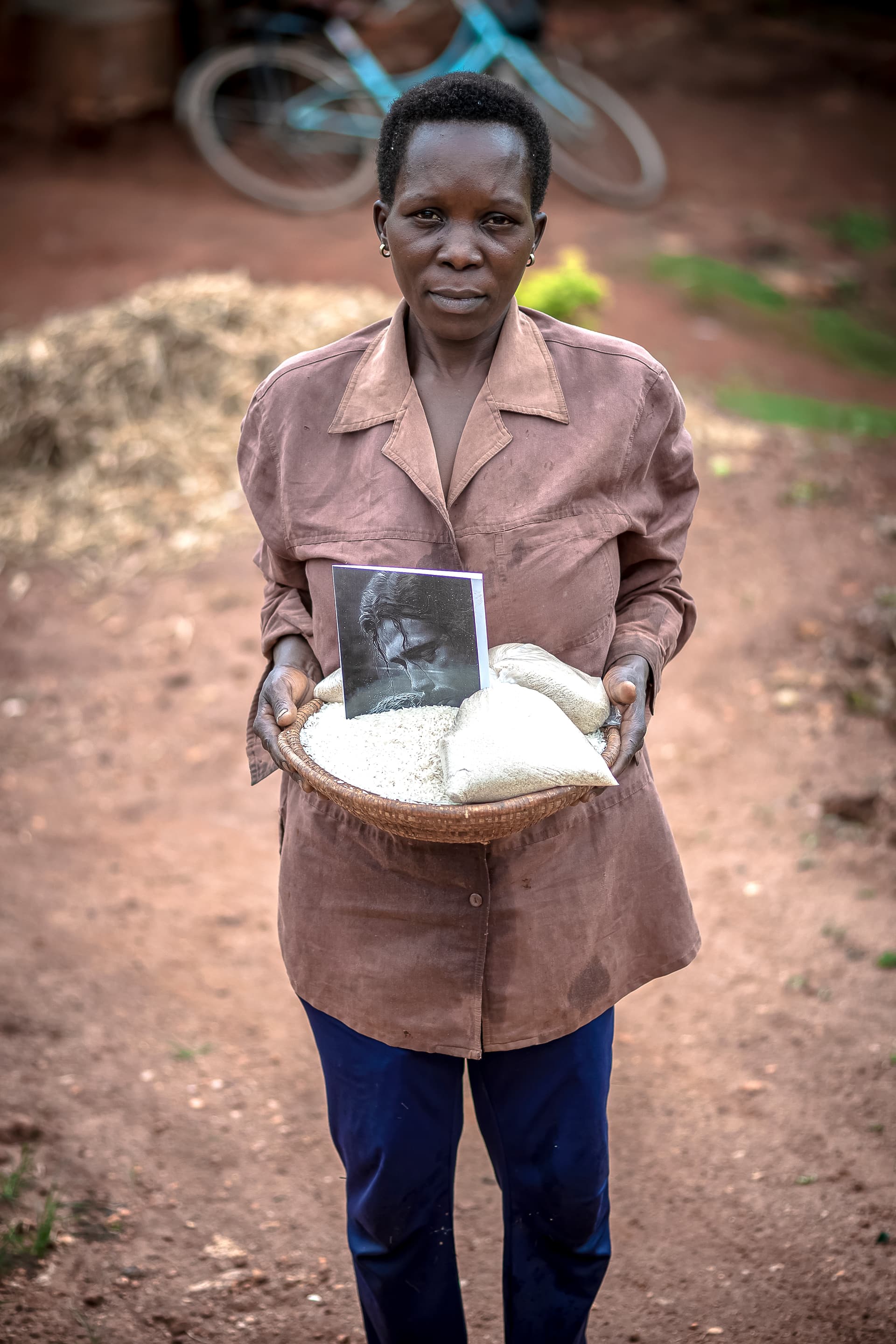 A woman stands outdoors holding a plate with food items and a small printed photo.