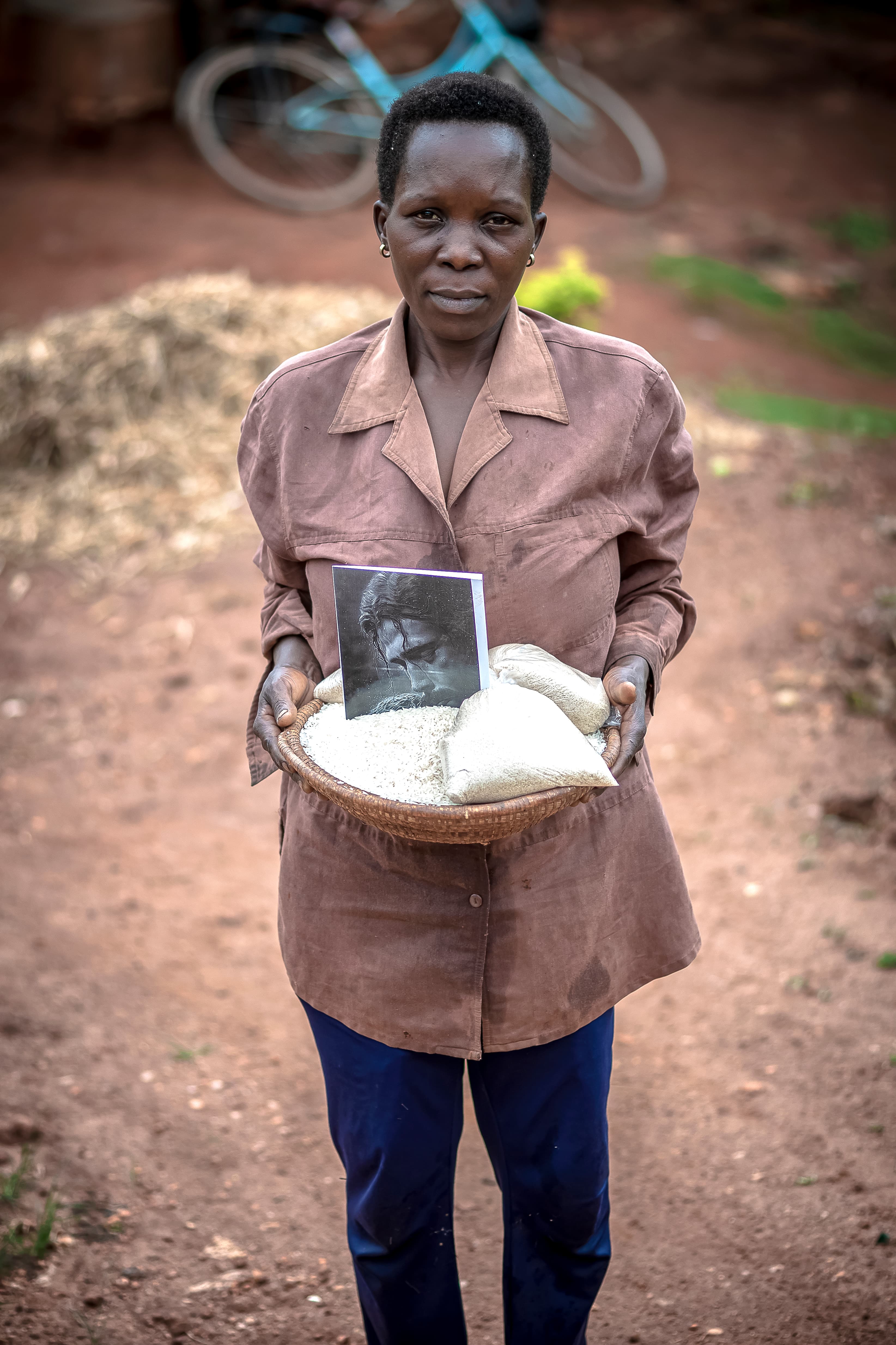 A woman stands outdoors holding a plate with food items and a small printed photo.