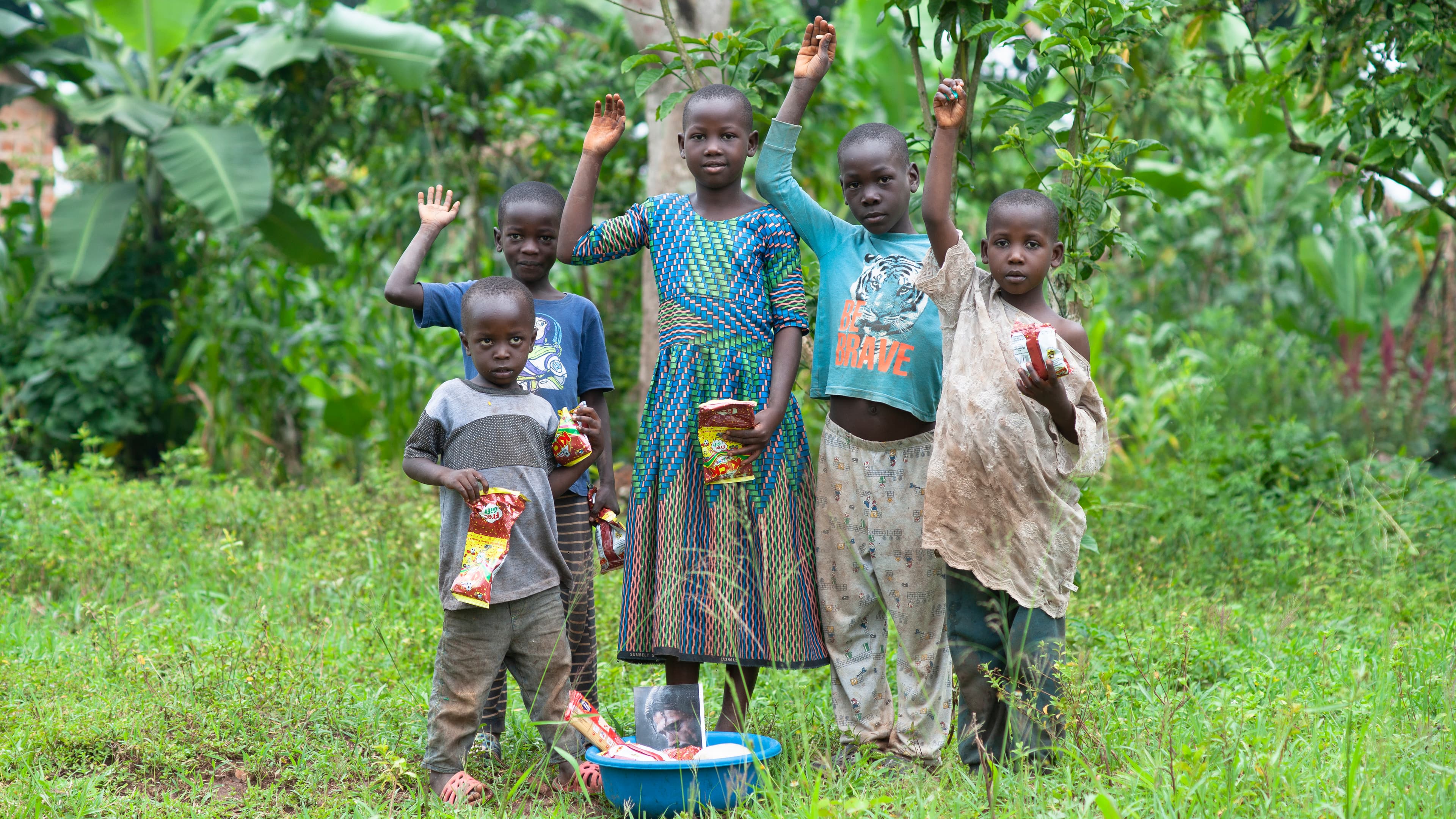 A group of children walk together across an open green field.