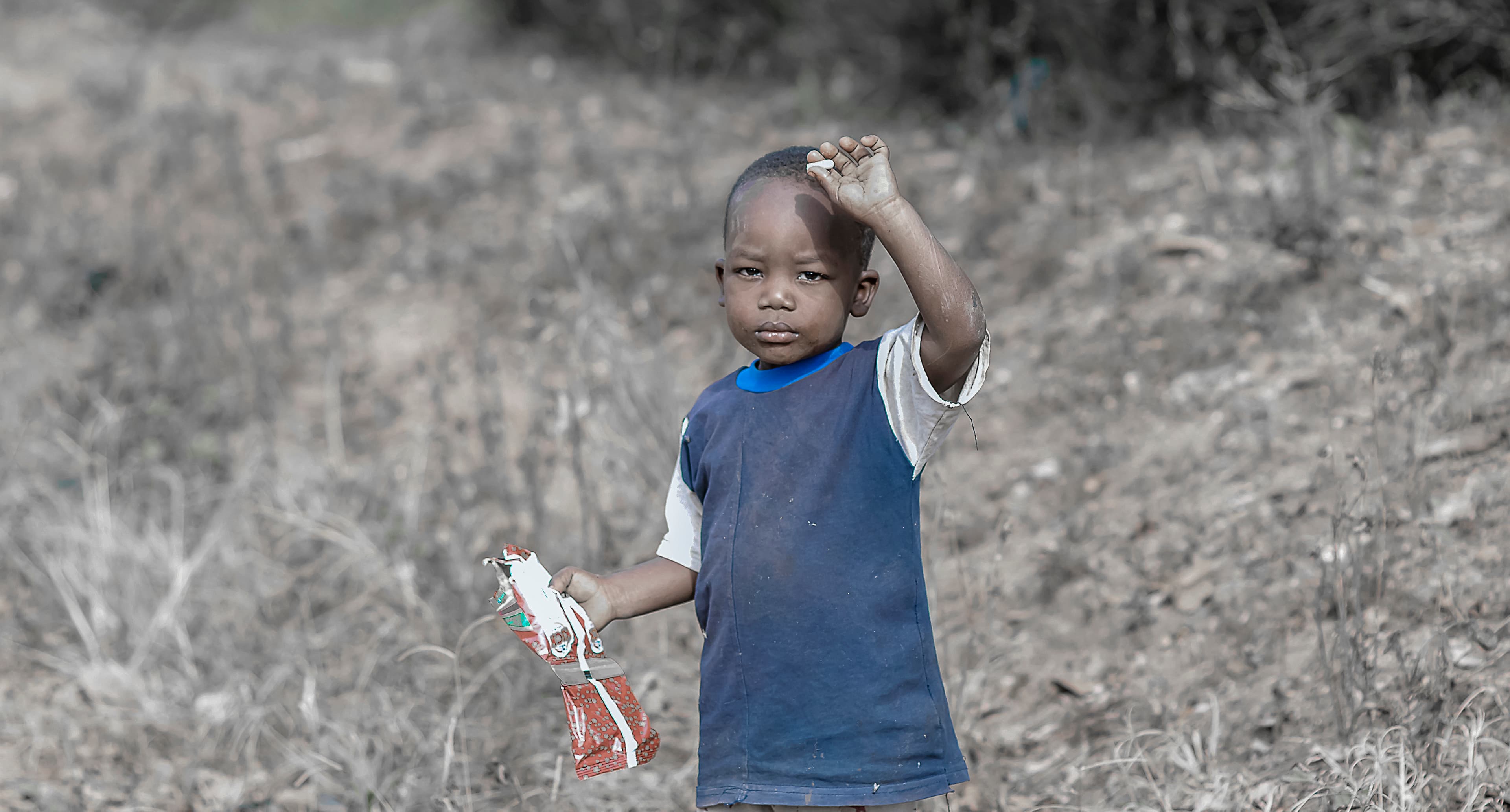 Black-and-white photo of a child raising a hand outdoors.