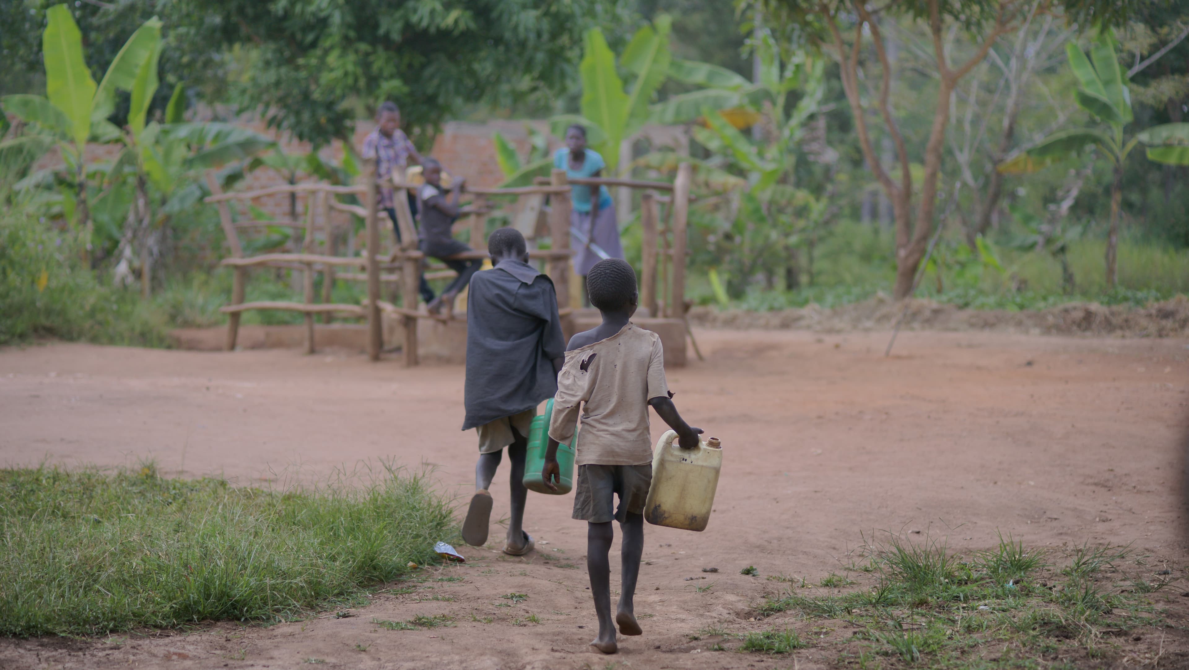 Children walking together down a dirt path near a wooden fence