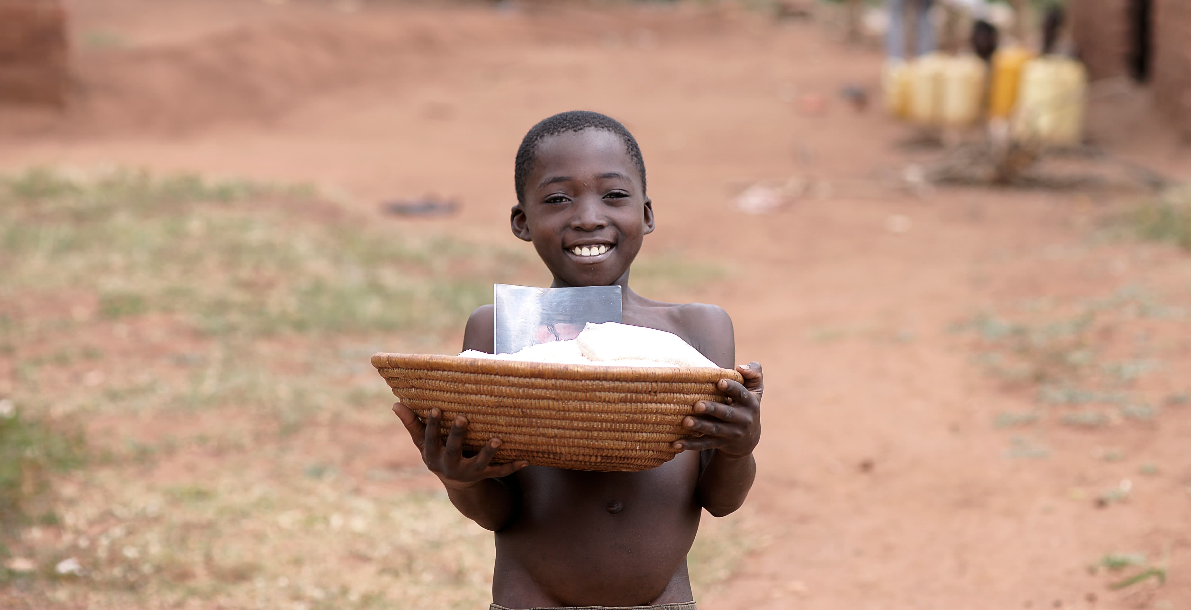 Smiling child holding a woven basket outdoors