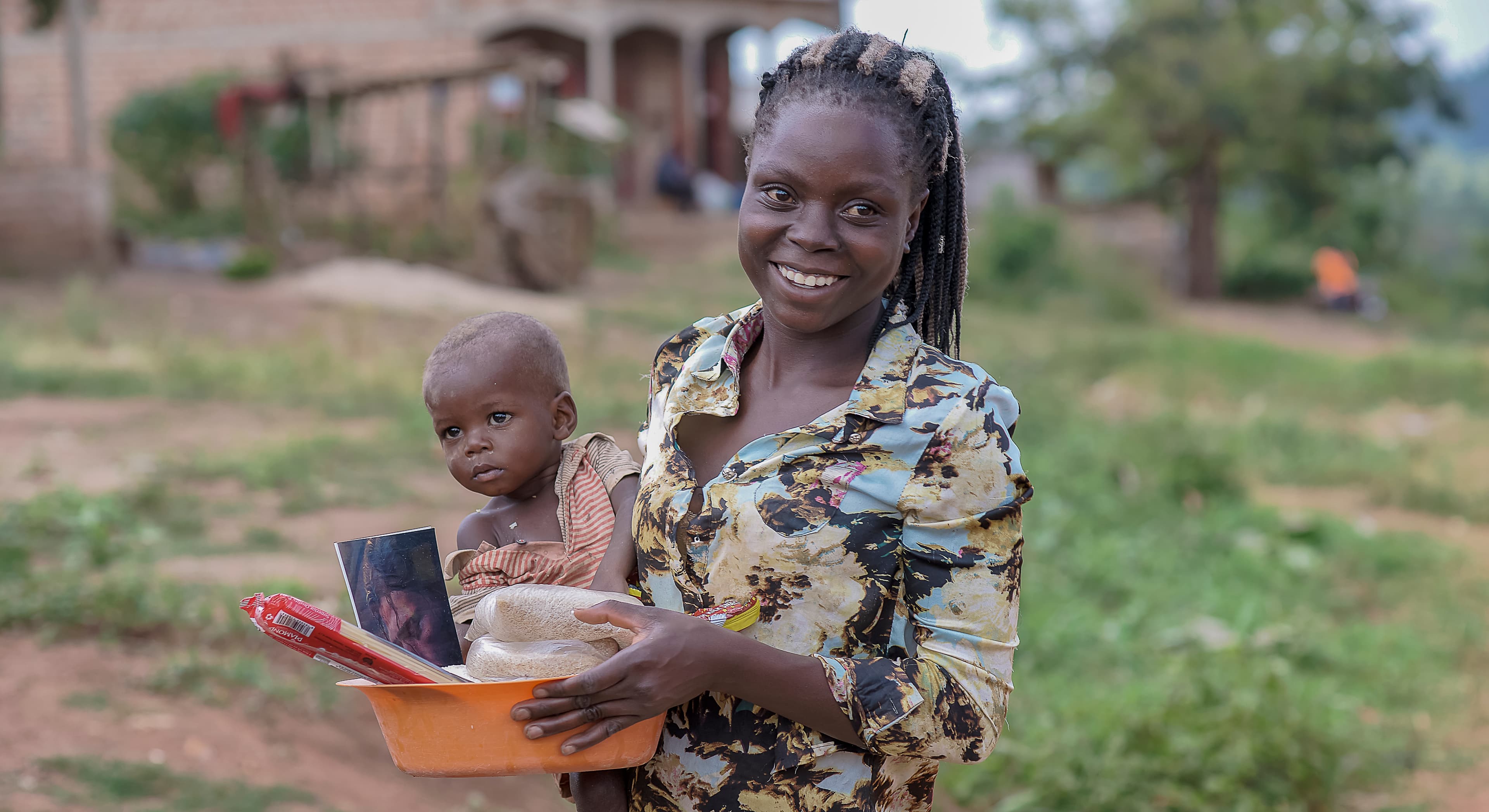 Woman and small child standing together outdoors, the child holding a food item