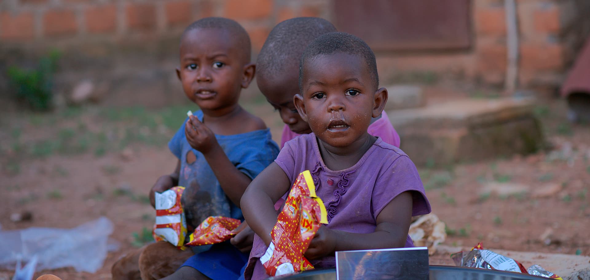 Close-up of two young children seated behind their food bowls at the distribution event