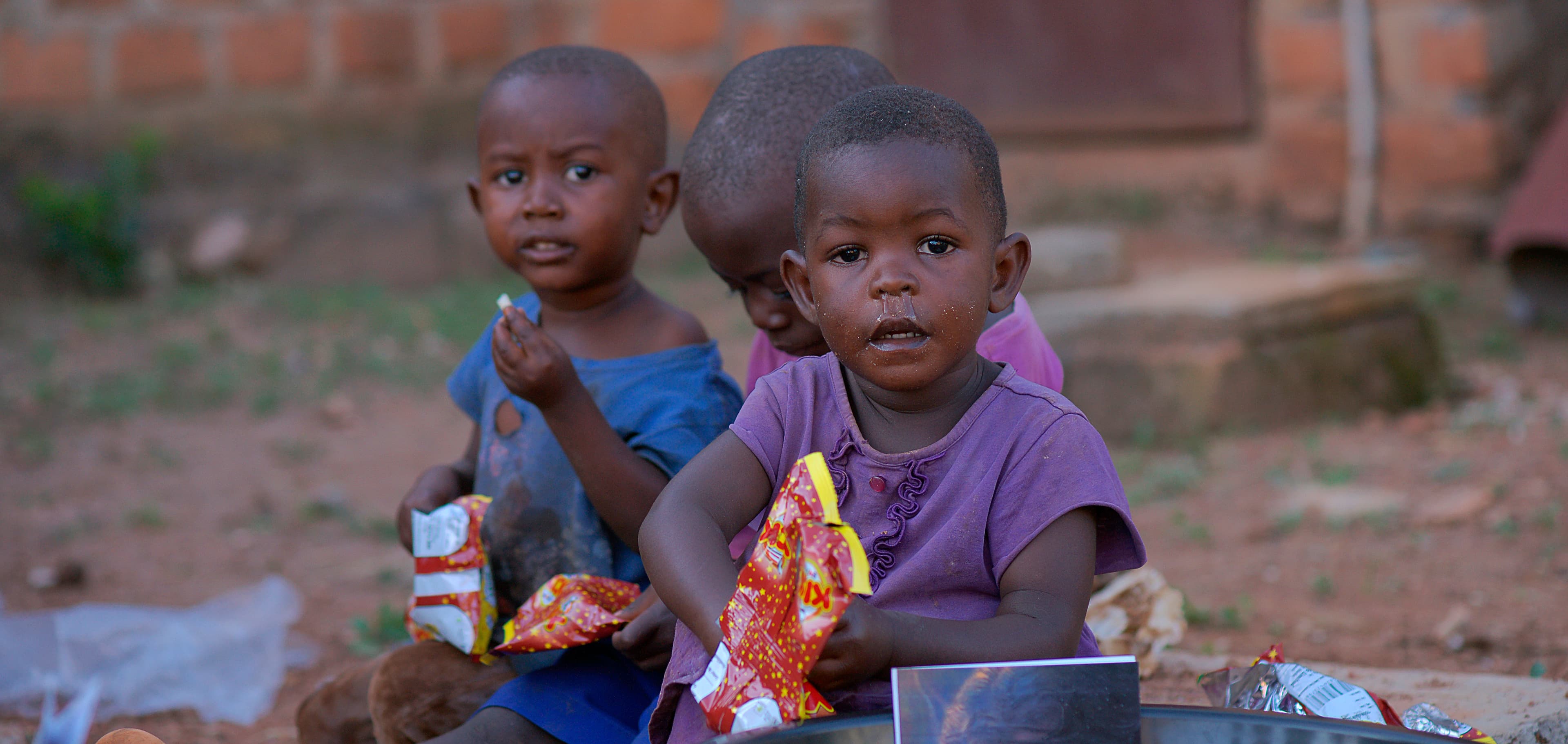 Close-up of two young children seated behind their food bowls at the distribution event