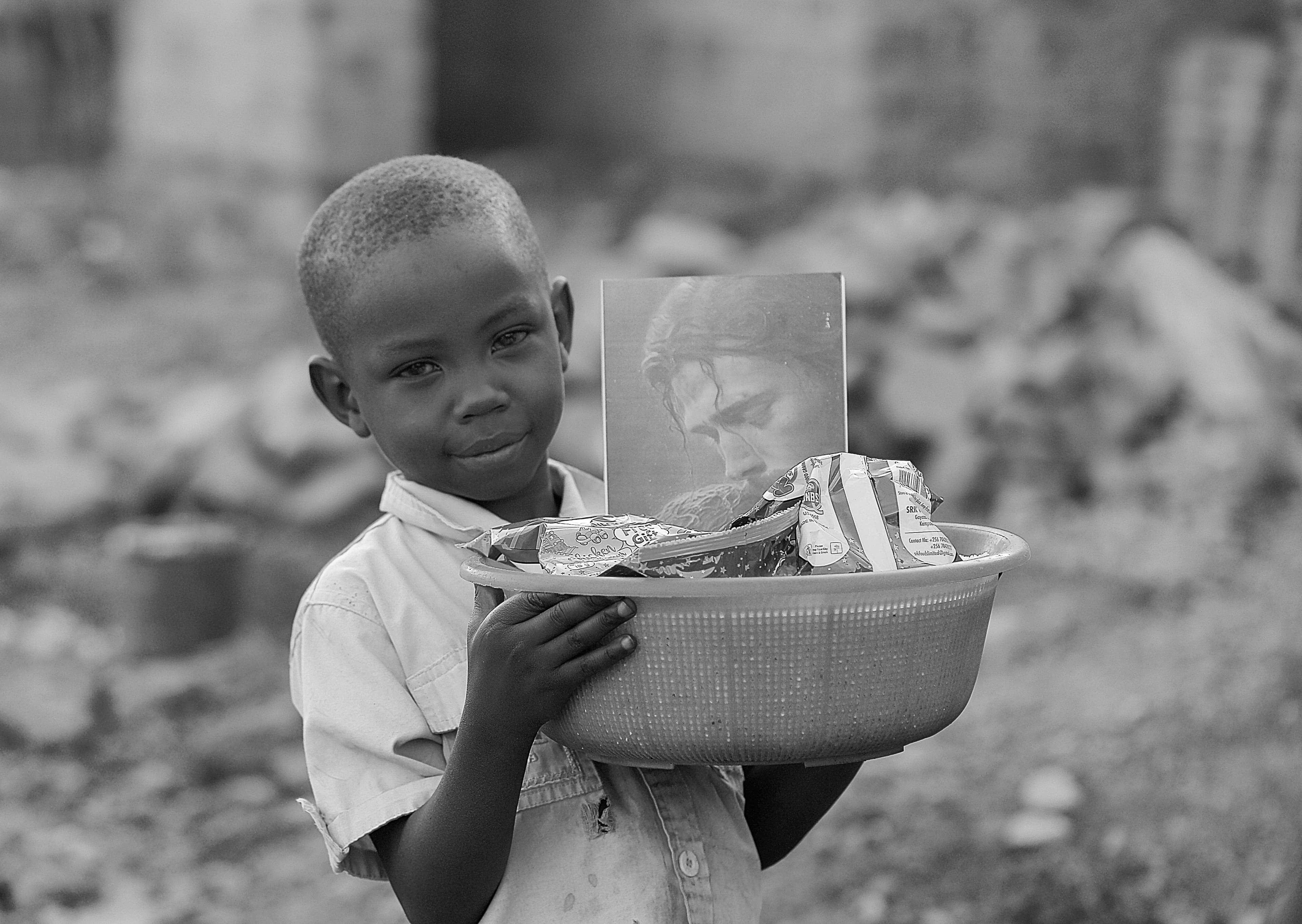 Black and white photo of a child holding a bowl of food, looking downward