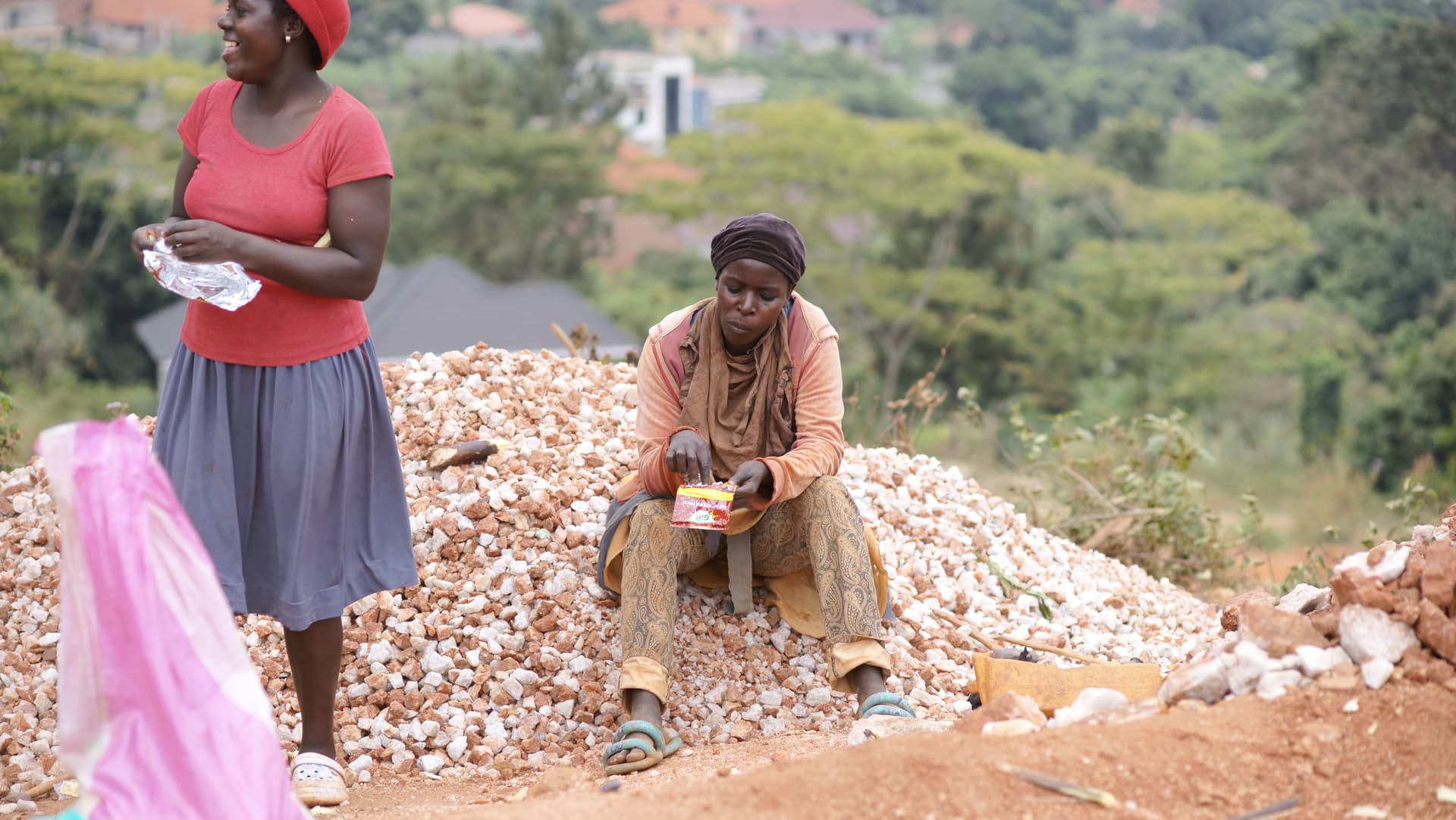 Woman in a red top and a man sit together on a pile of rocks at the quarry.