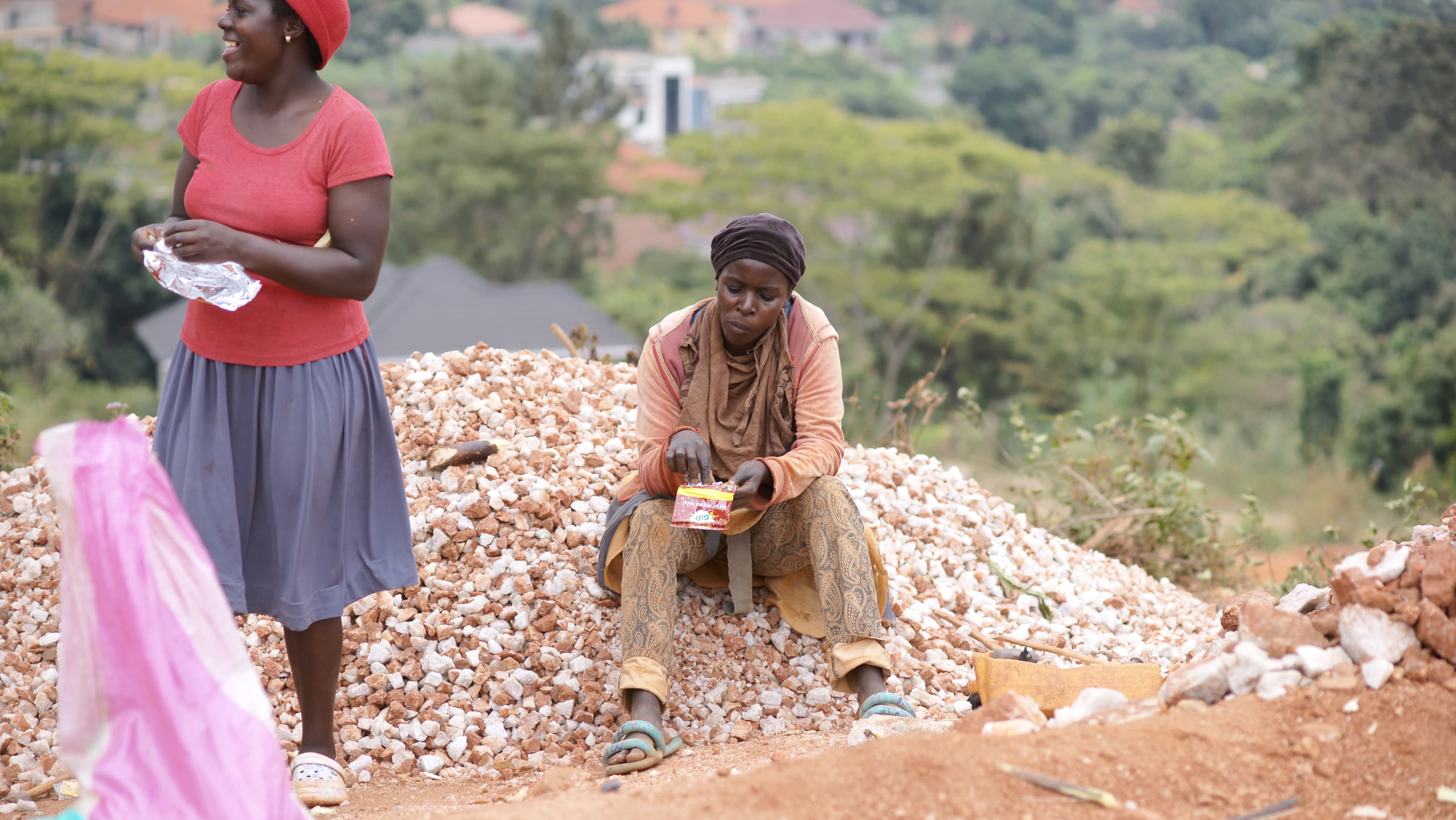 Woman in a red top and a man sit together on a pile of rocks at the quarry.