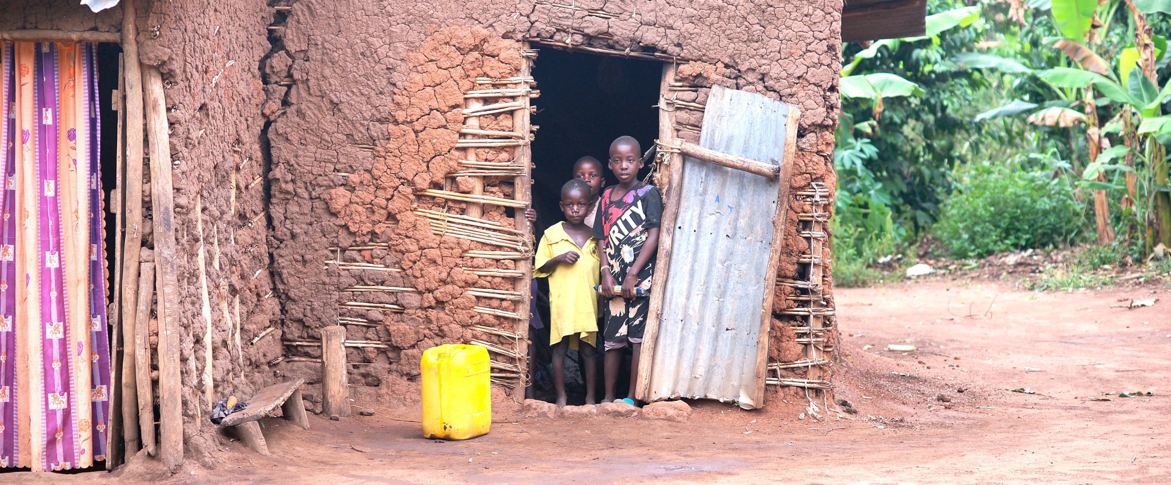 Family stands at the doorway of a brick home decorated with a colorful fabric curtain.