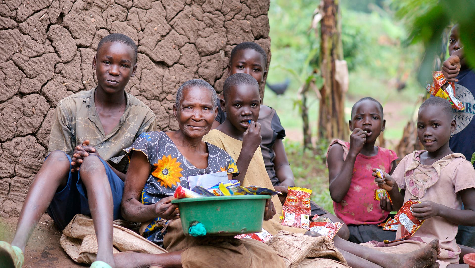Elderly people and children gather outside, some holding food items.