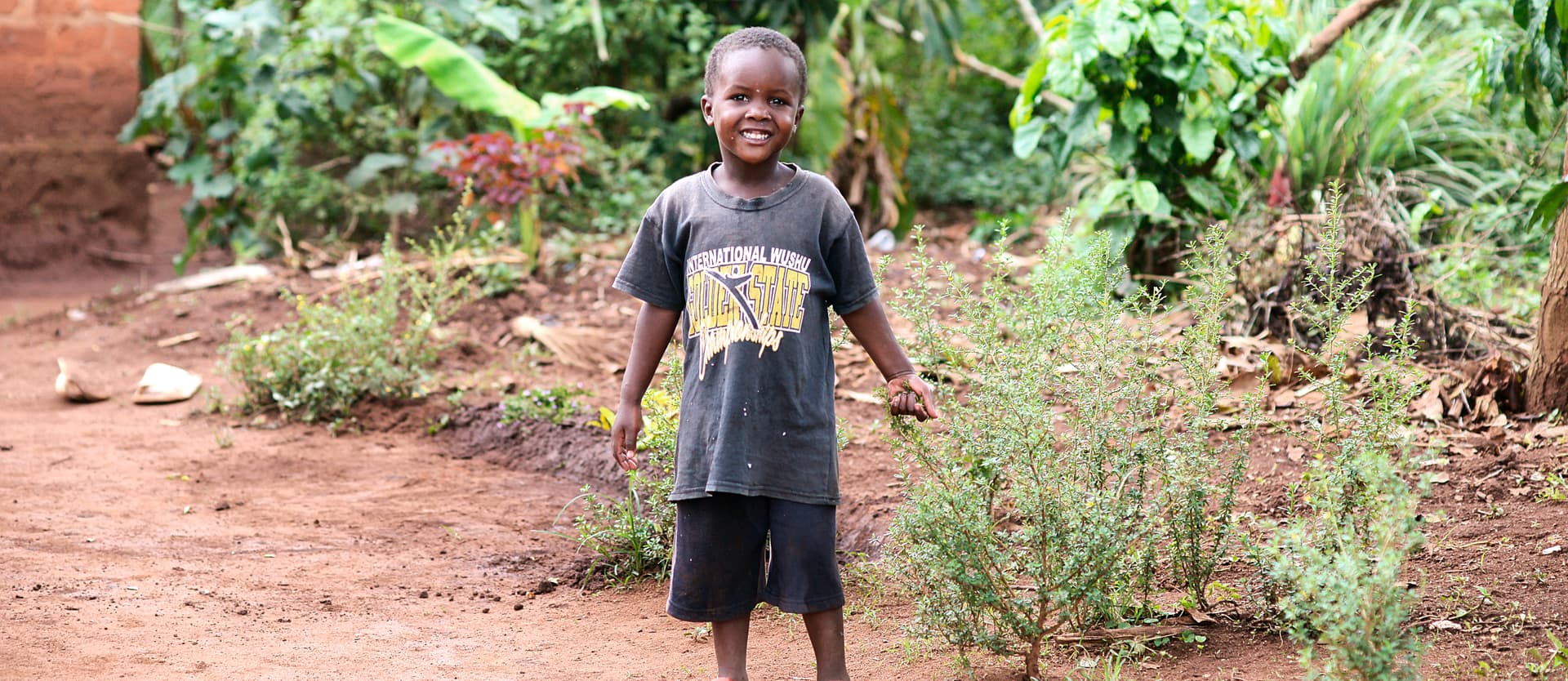 Boy stands in an open field holding food items.