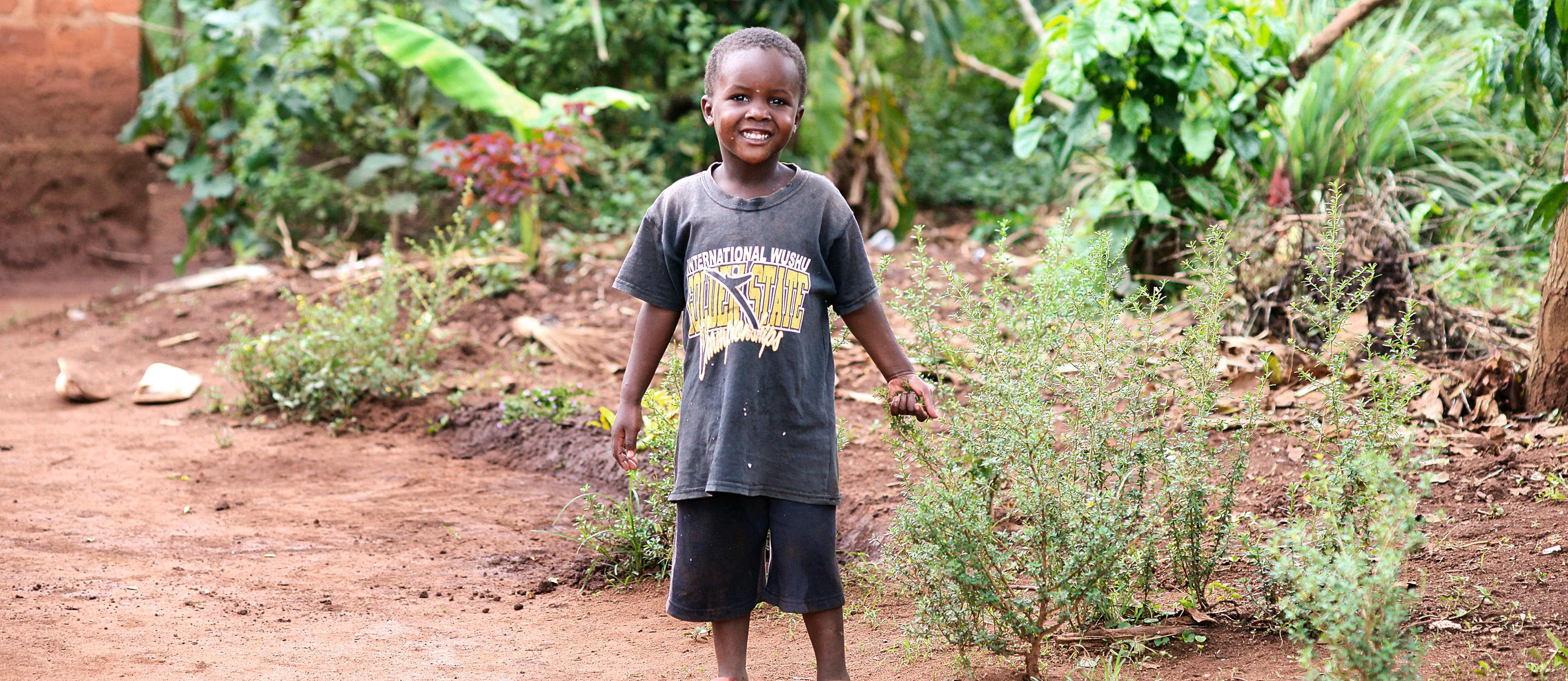 Boy stands in an open field holding food items.
