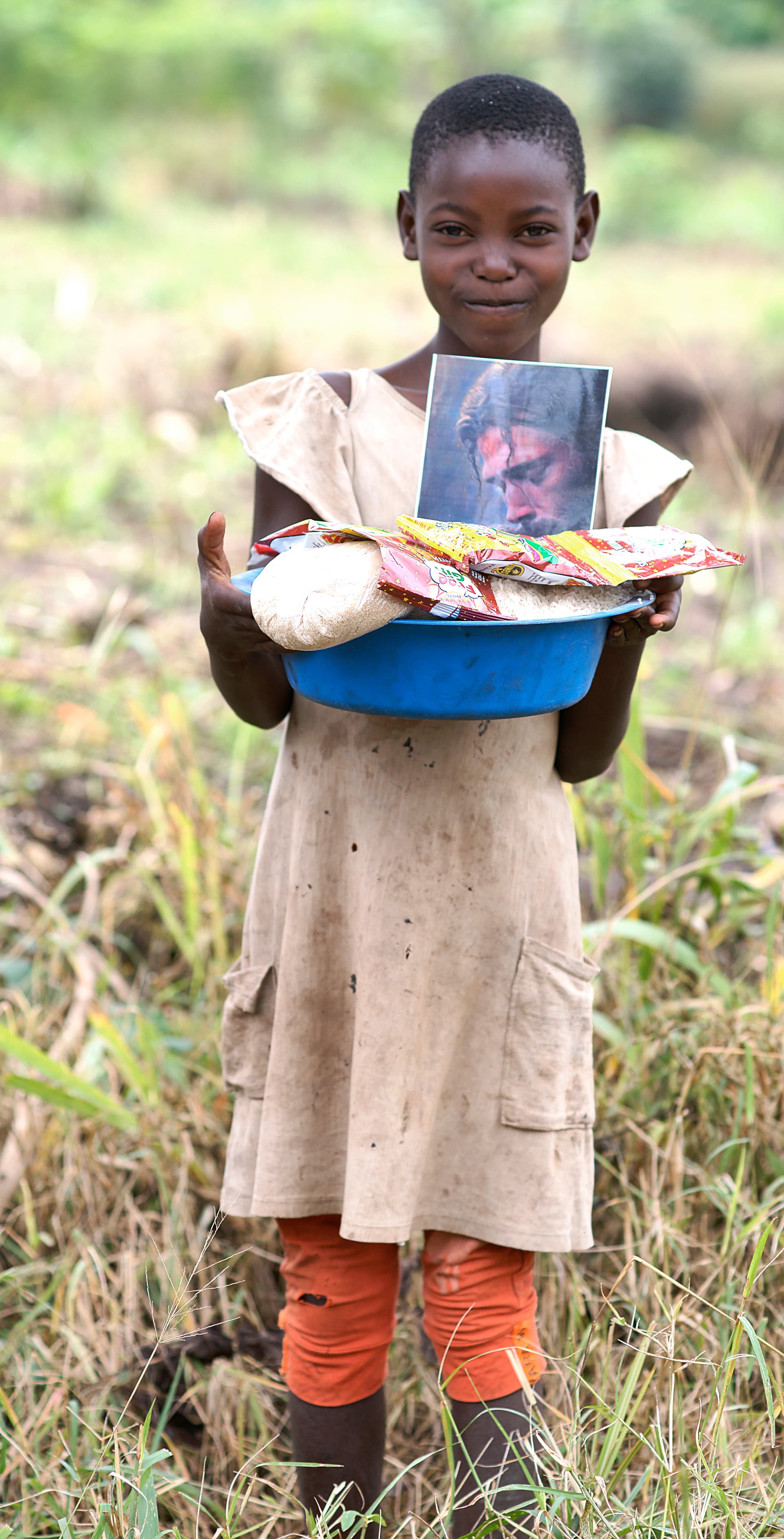 Motion-blurred photo of a boy holding a basin of food topped with a photo card.