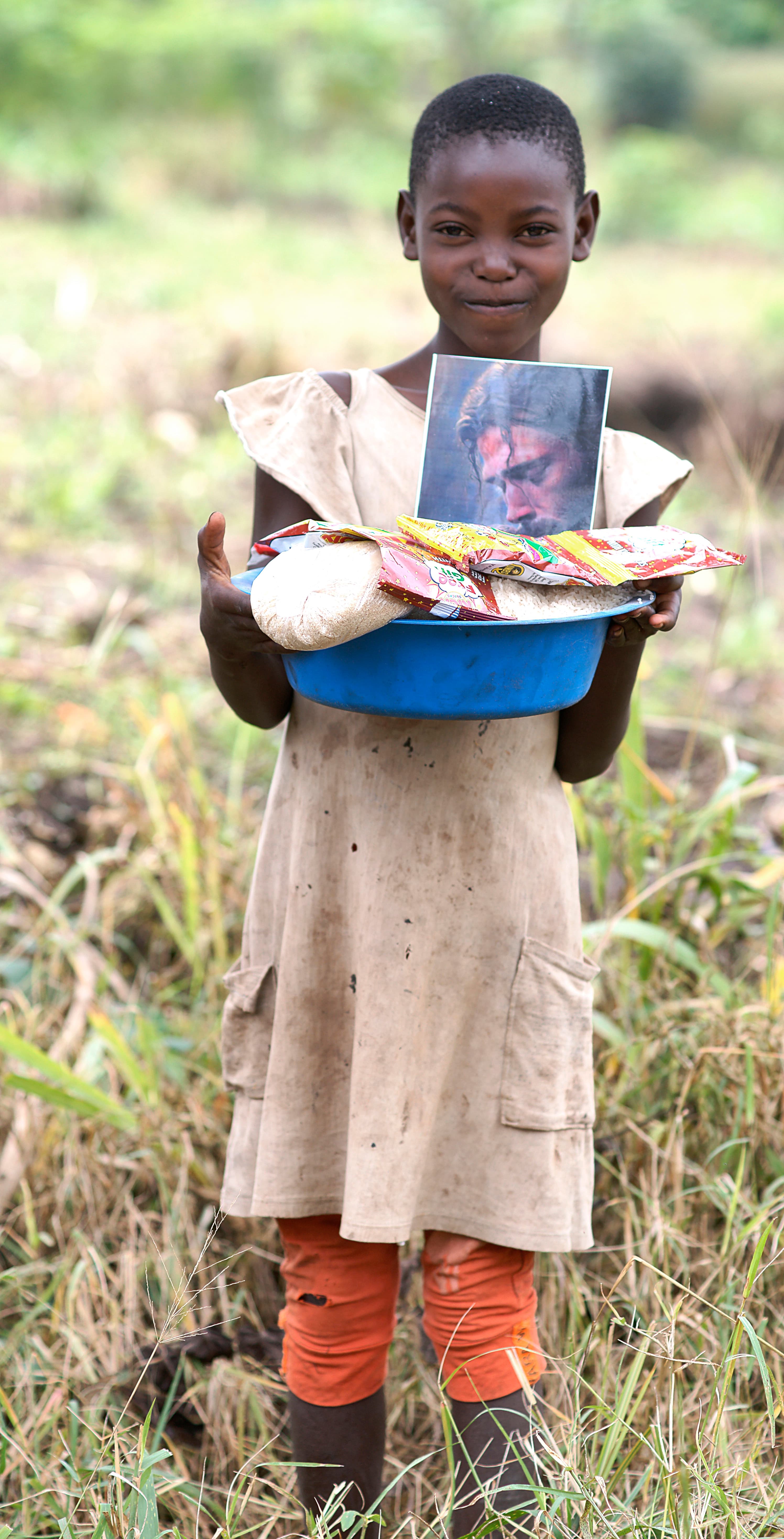 Motion-blurred photo of a boy holding a basin of food topped with a photo card.