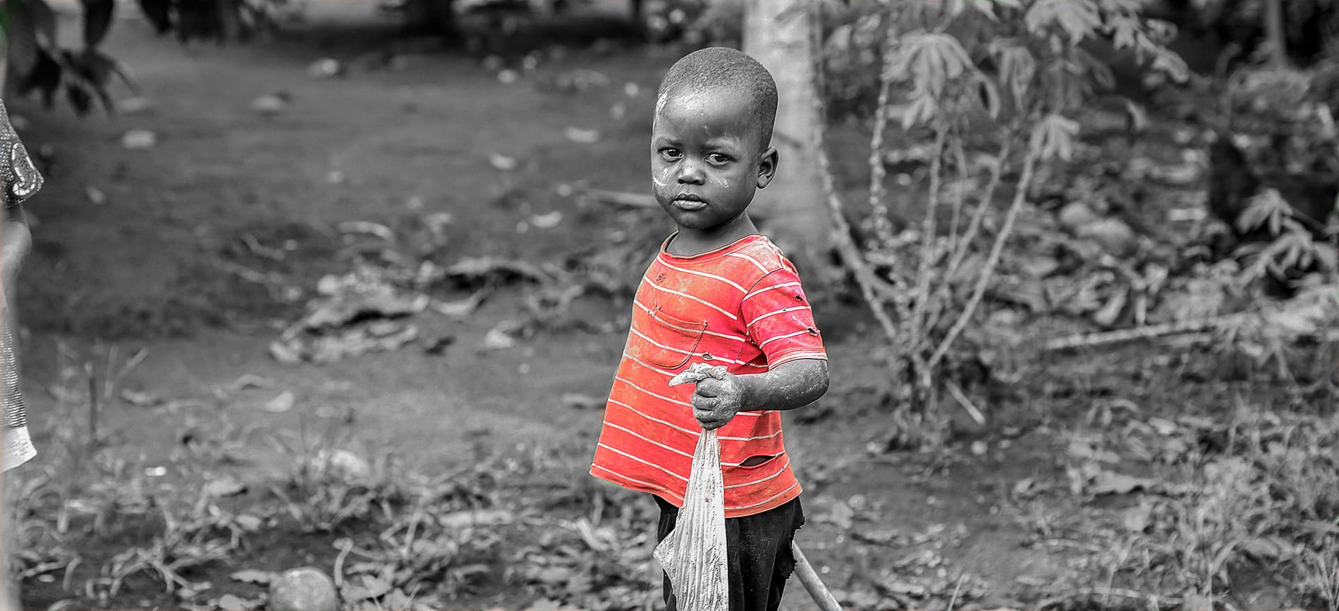 Black-and-white photo of a young boy standing alone outdoors.
