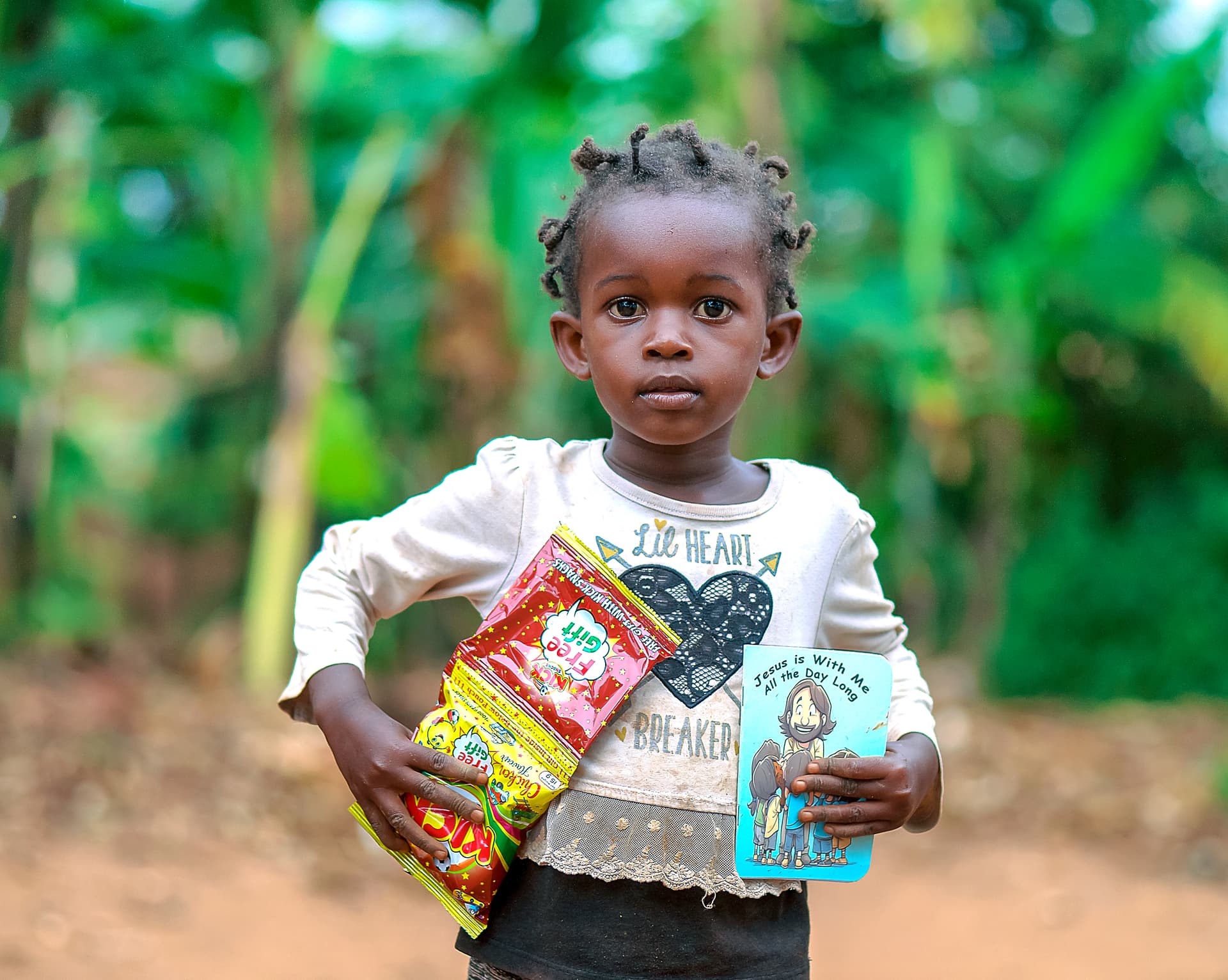 A young girl smiles while holding a food package and a booklet.
