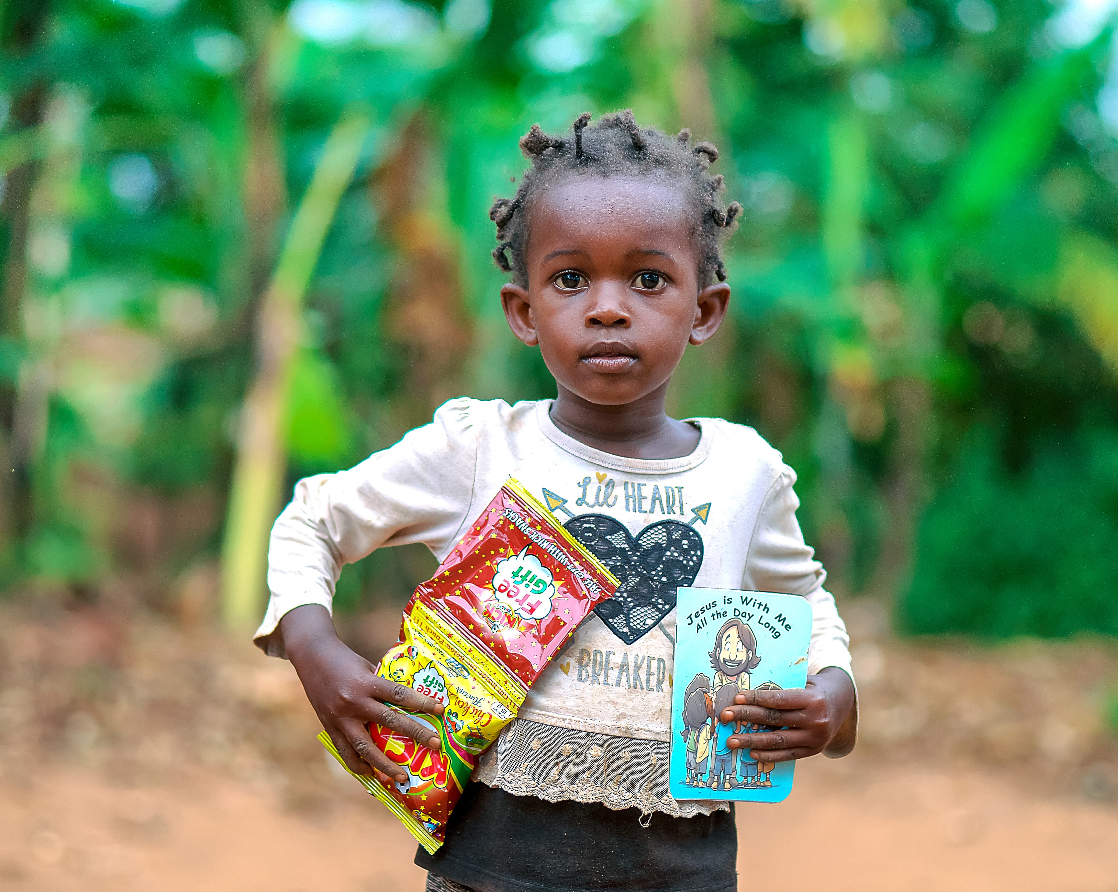 A young girl smiles while holding a food package and a booklet.