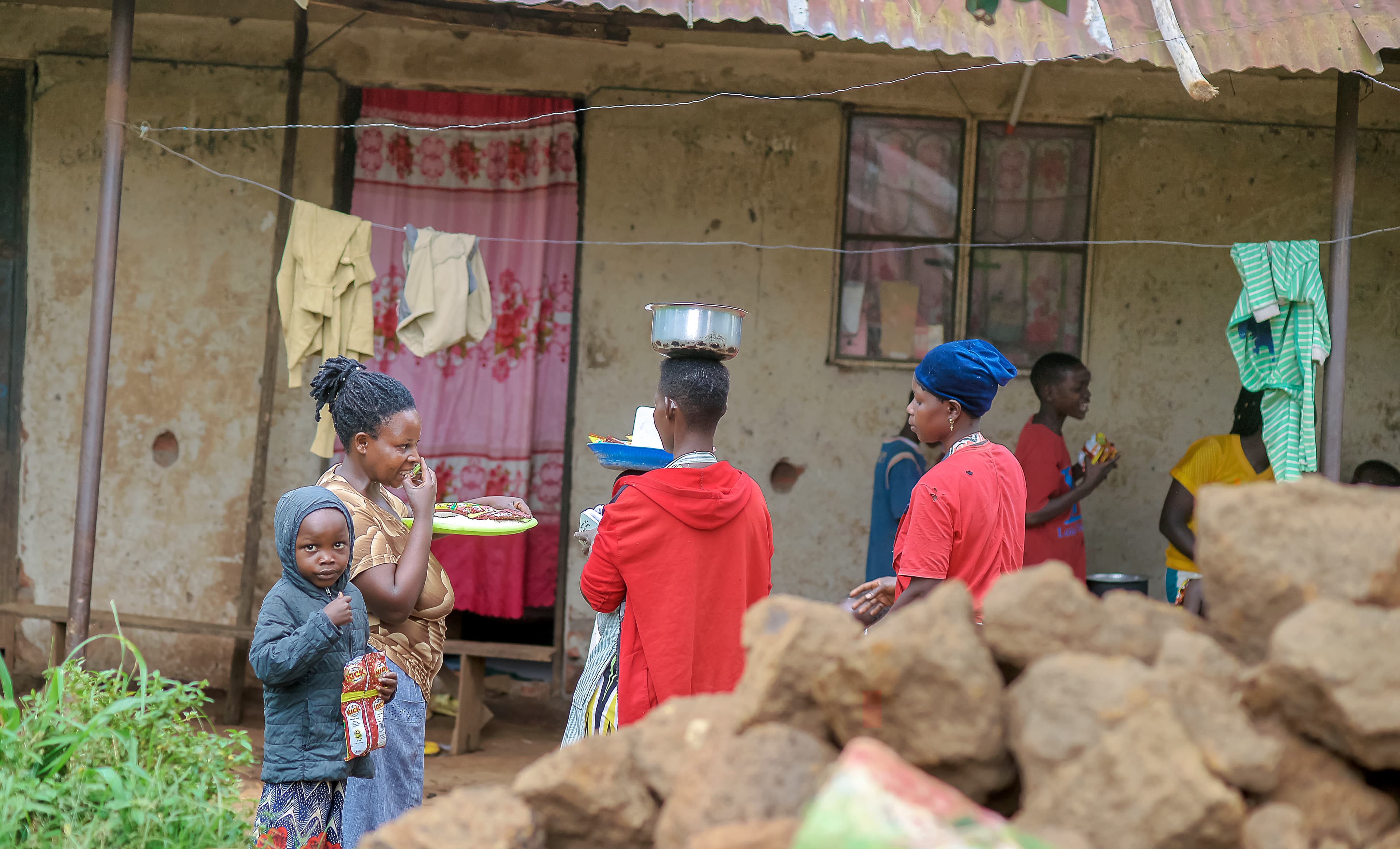 A small group of elderly people sit together under a thatched shelter.