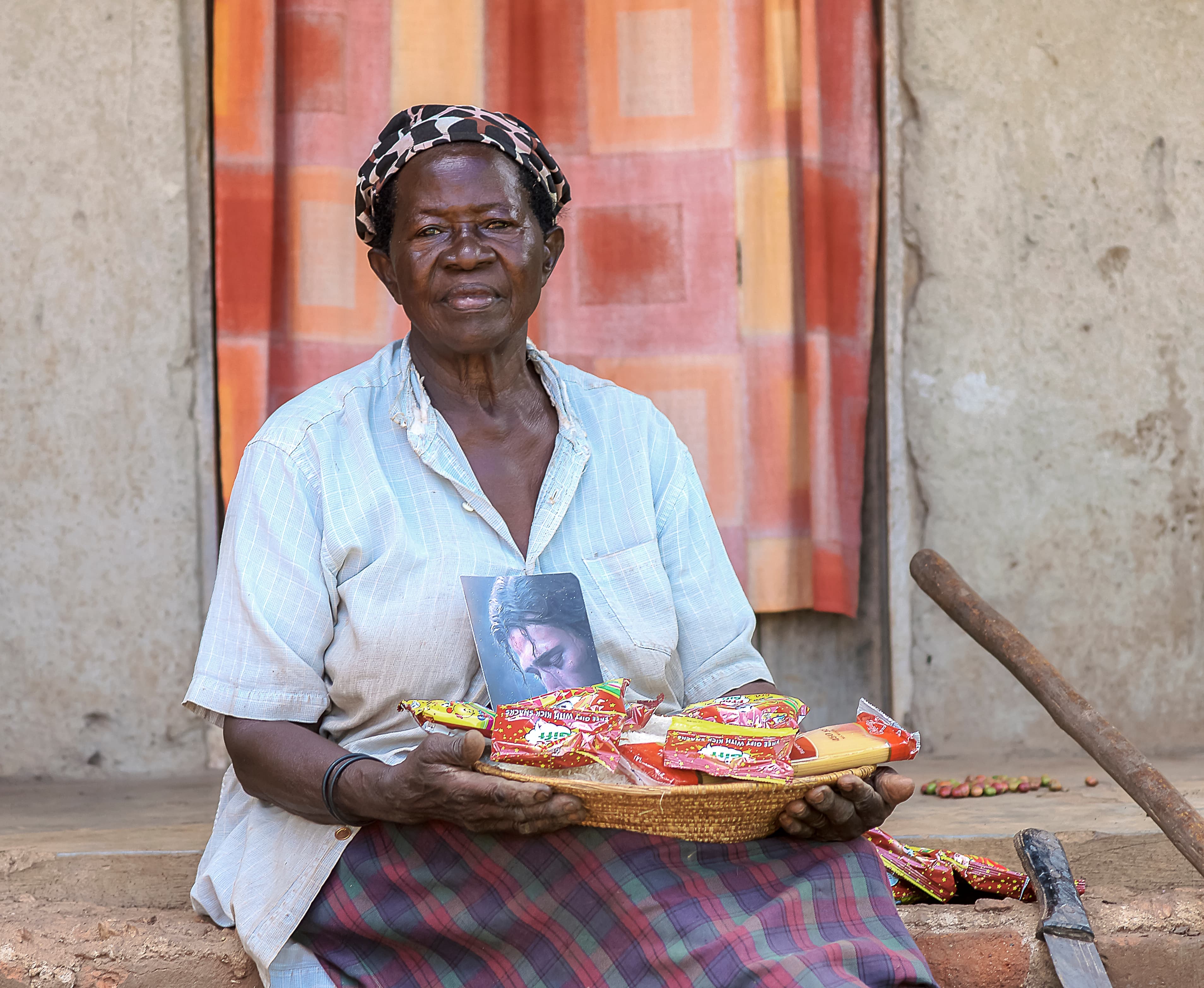 Elder Rose Mary sits holding a basket of food gifts and a booklet on her lap.