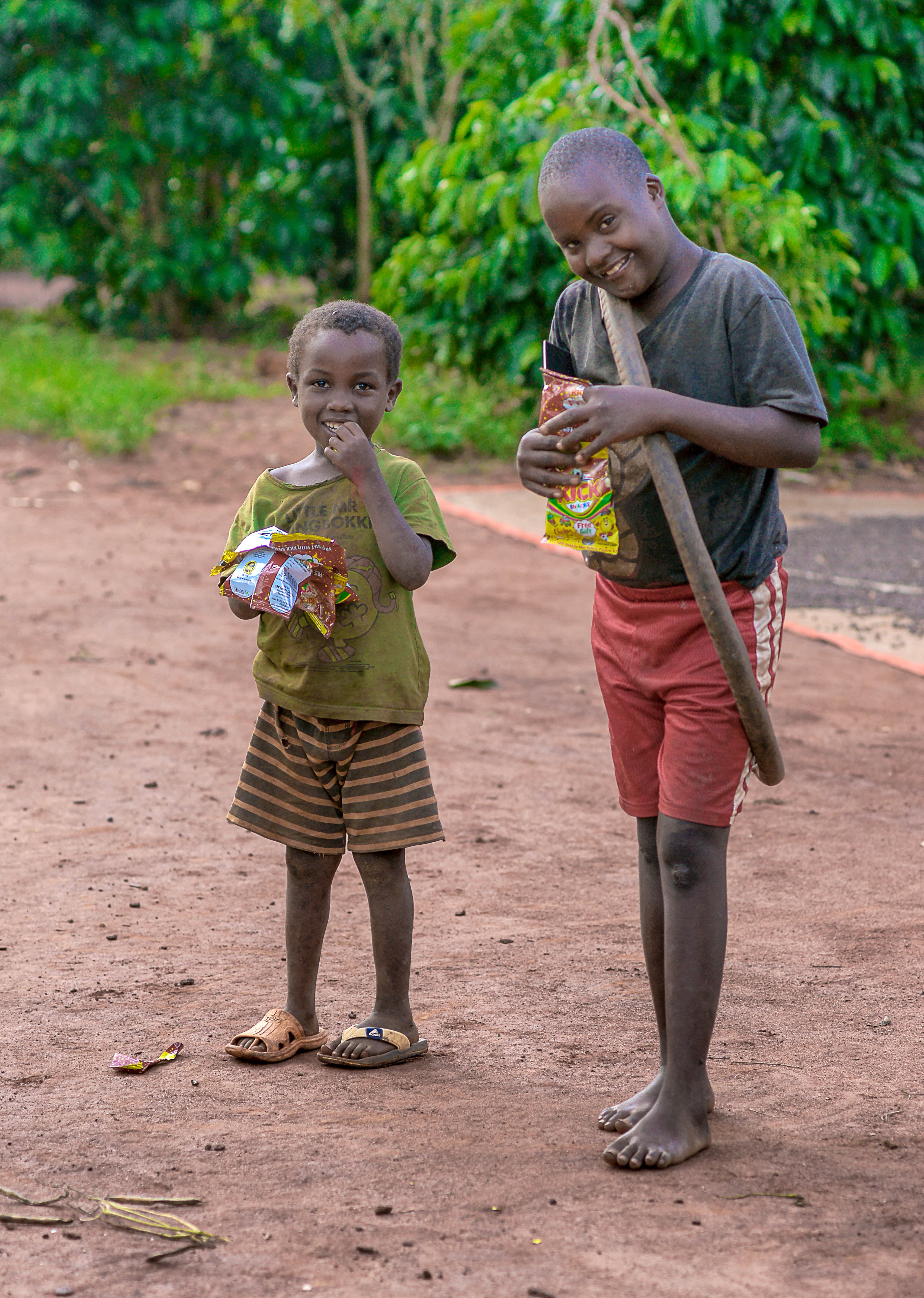 Two boys stand together outdoors, one holding a JFM food gift package.