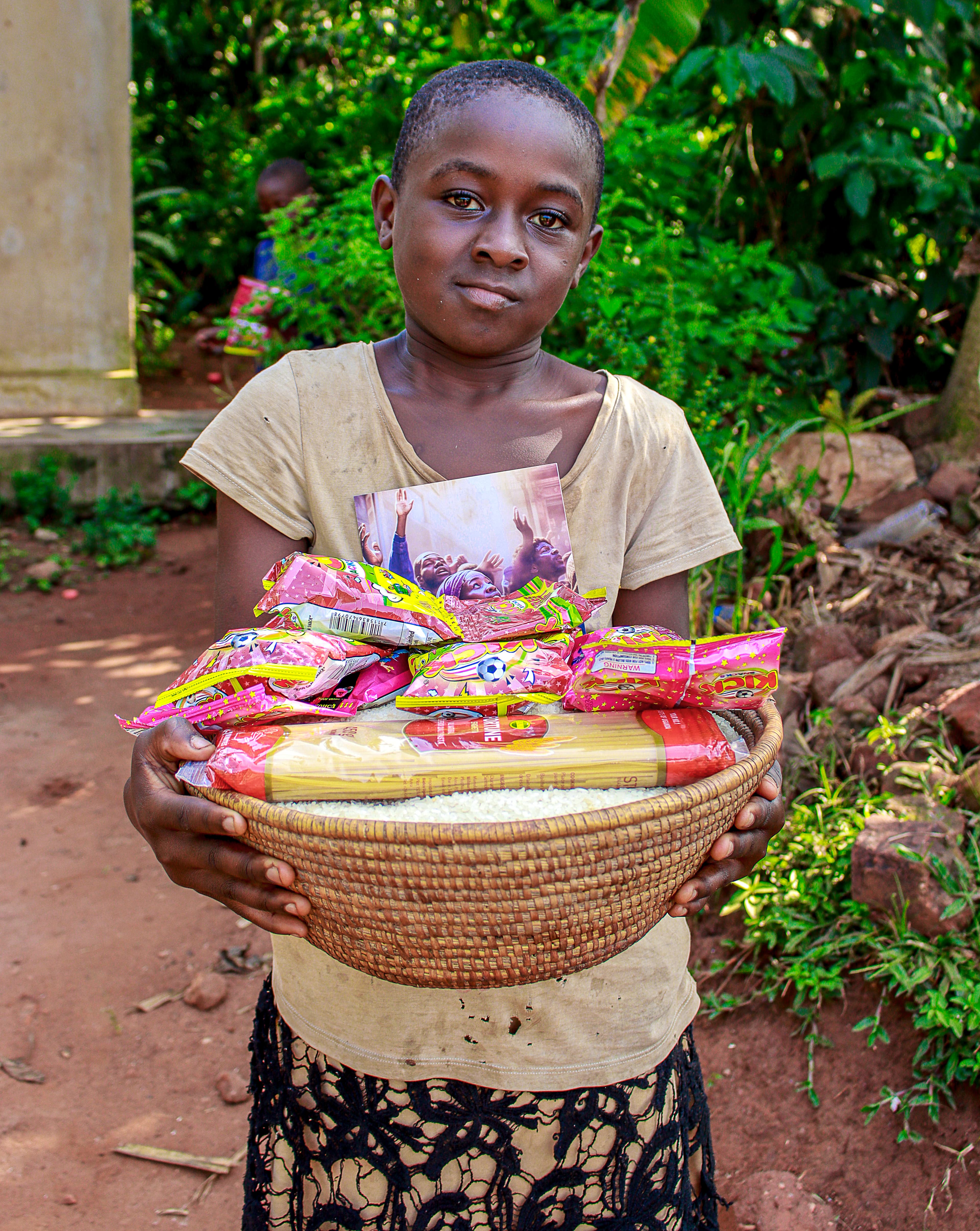 Girl holding a woven basket filled with food packets outdoors