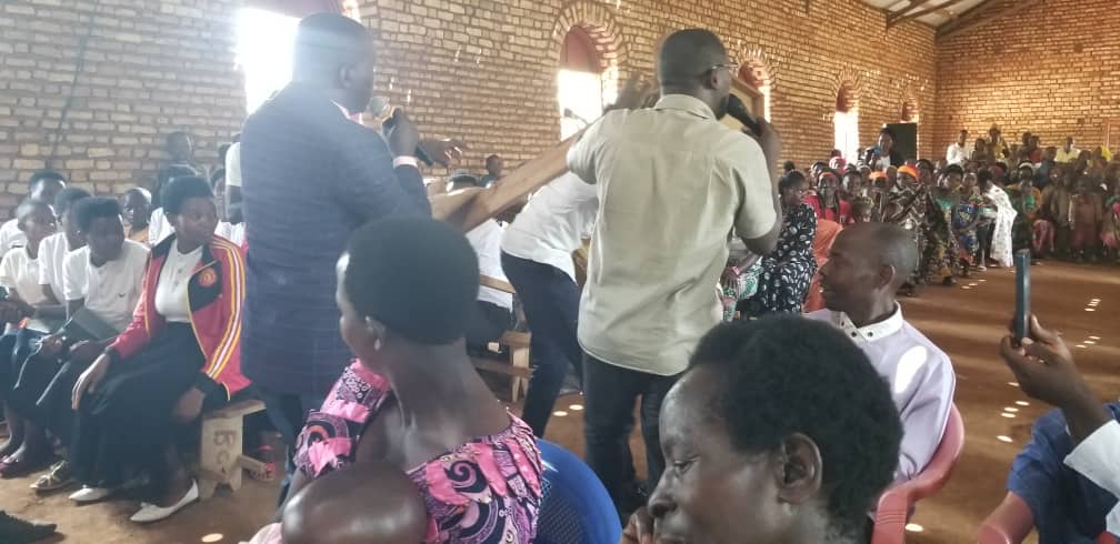 People kneel and bow in the aisle of a brick church during worship.