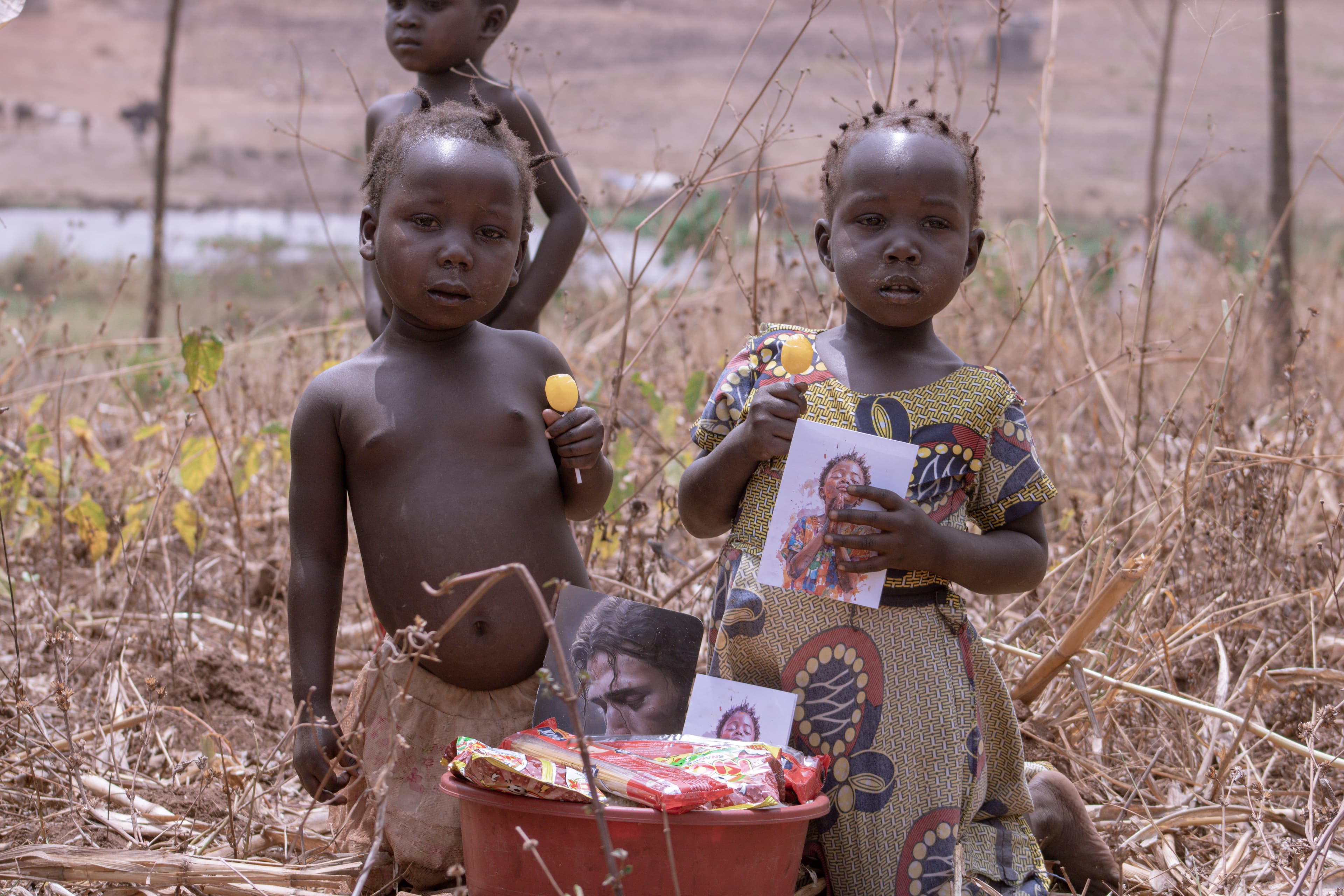 Two young children standing outdoors near a basin of food and gospel tracts.