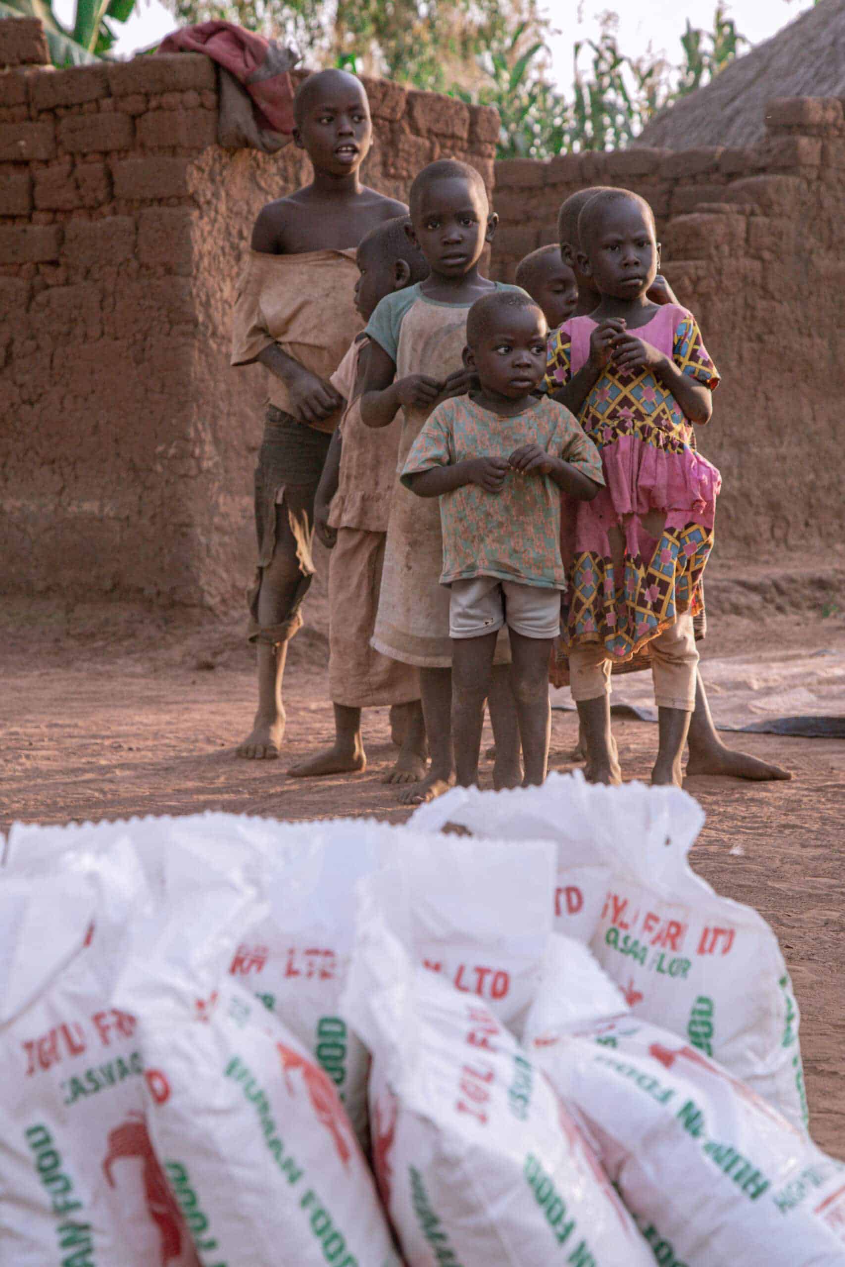 Bags of food supplies stacked in front of a brick building.