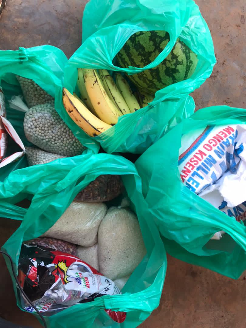 Green plastic bags filled with watermelon and bananas sit ready for distribution.