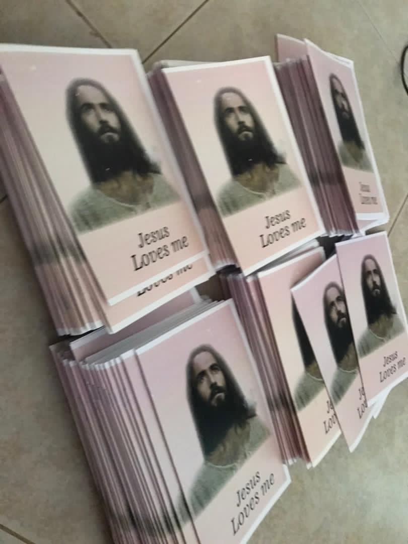 Stacks of freshly printed gospel tract booklets with a portrait of Jesus arranged on a shelf