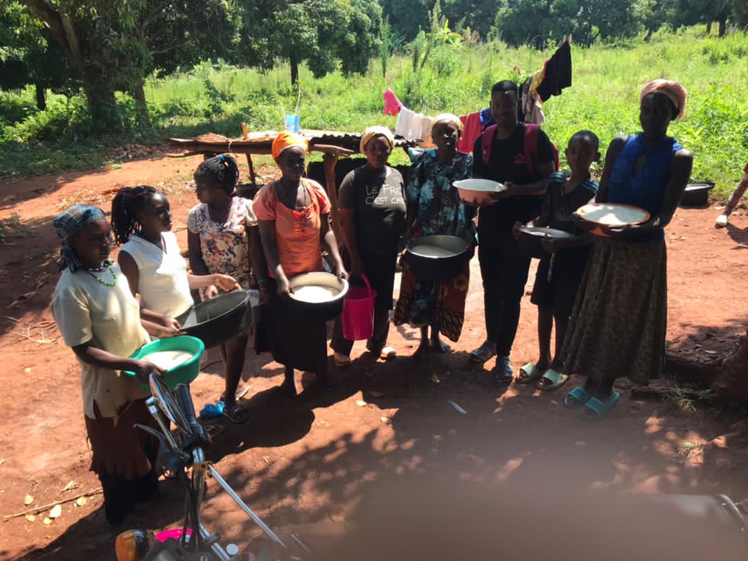 Line of women and children carrying plates of food with a gospel tract balanced on a plate