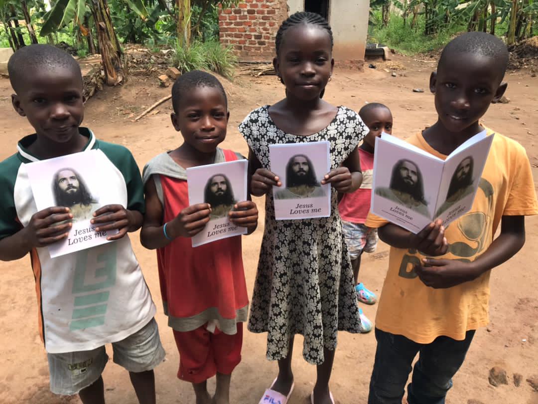 Two children holding gospel tract booklets with a portrait of Jesus, standing outdoors