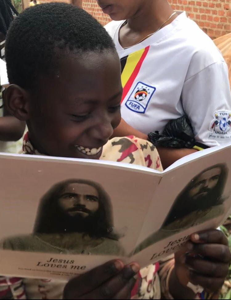 Child in a white uniform shirt reading a gospel tract booklet with a portrait of Jesus