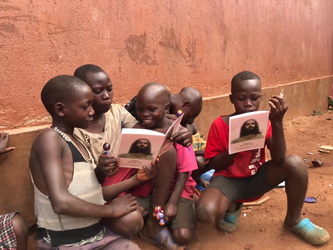 Two children seated together holding a gospel tract booklet with a portrait of Jesus