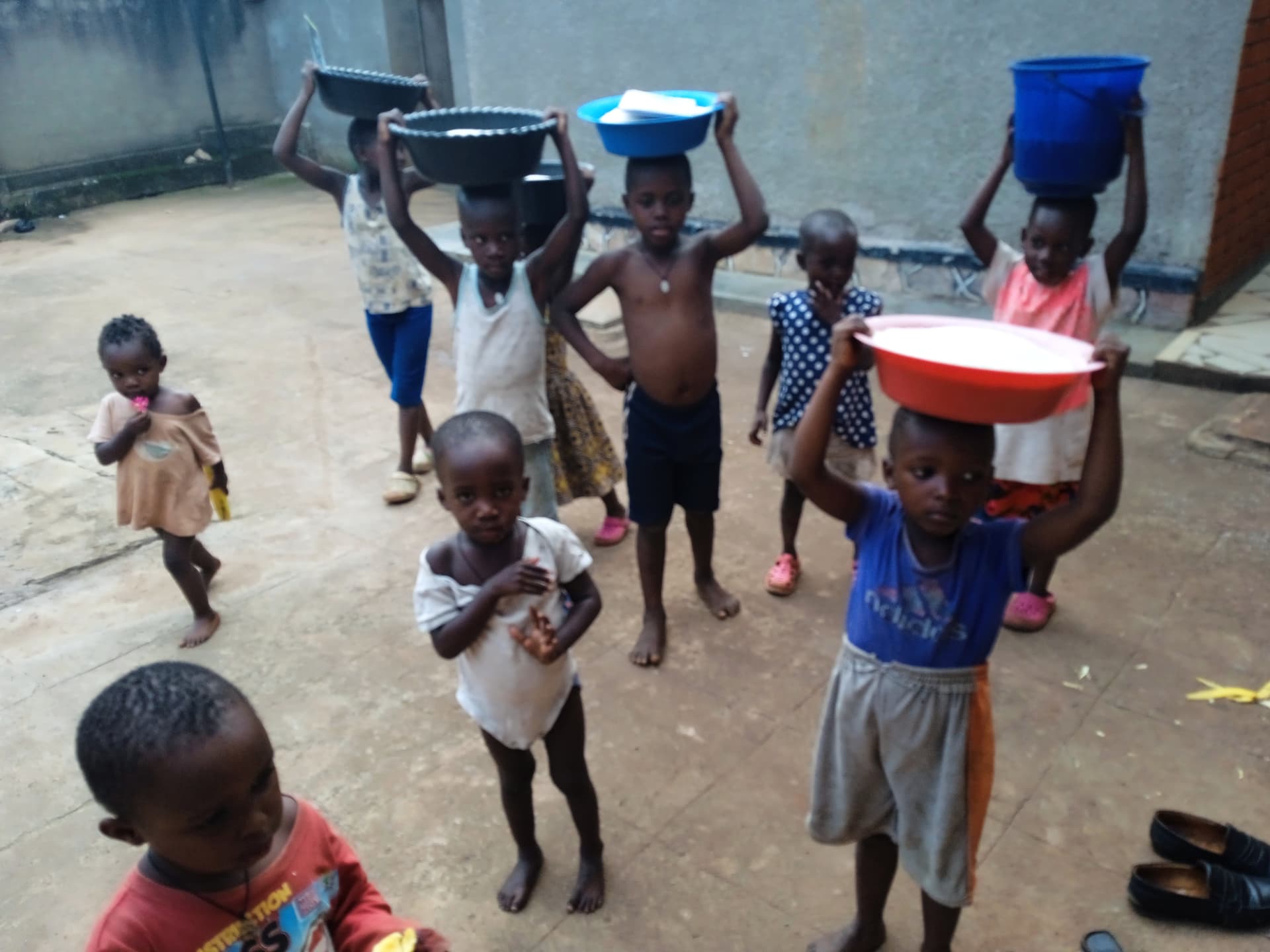 Aerial view of children carrying basins and buckets of rice on their heads.