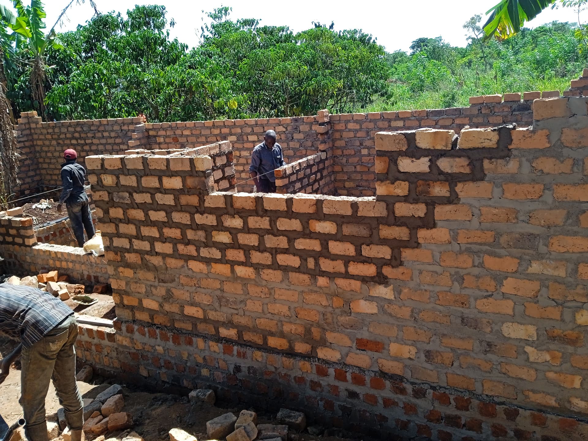 A worker stands atop a brick wall laying bricks during construction of Granny Angella's new house.