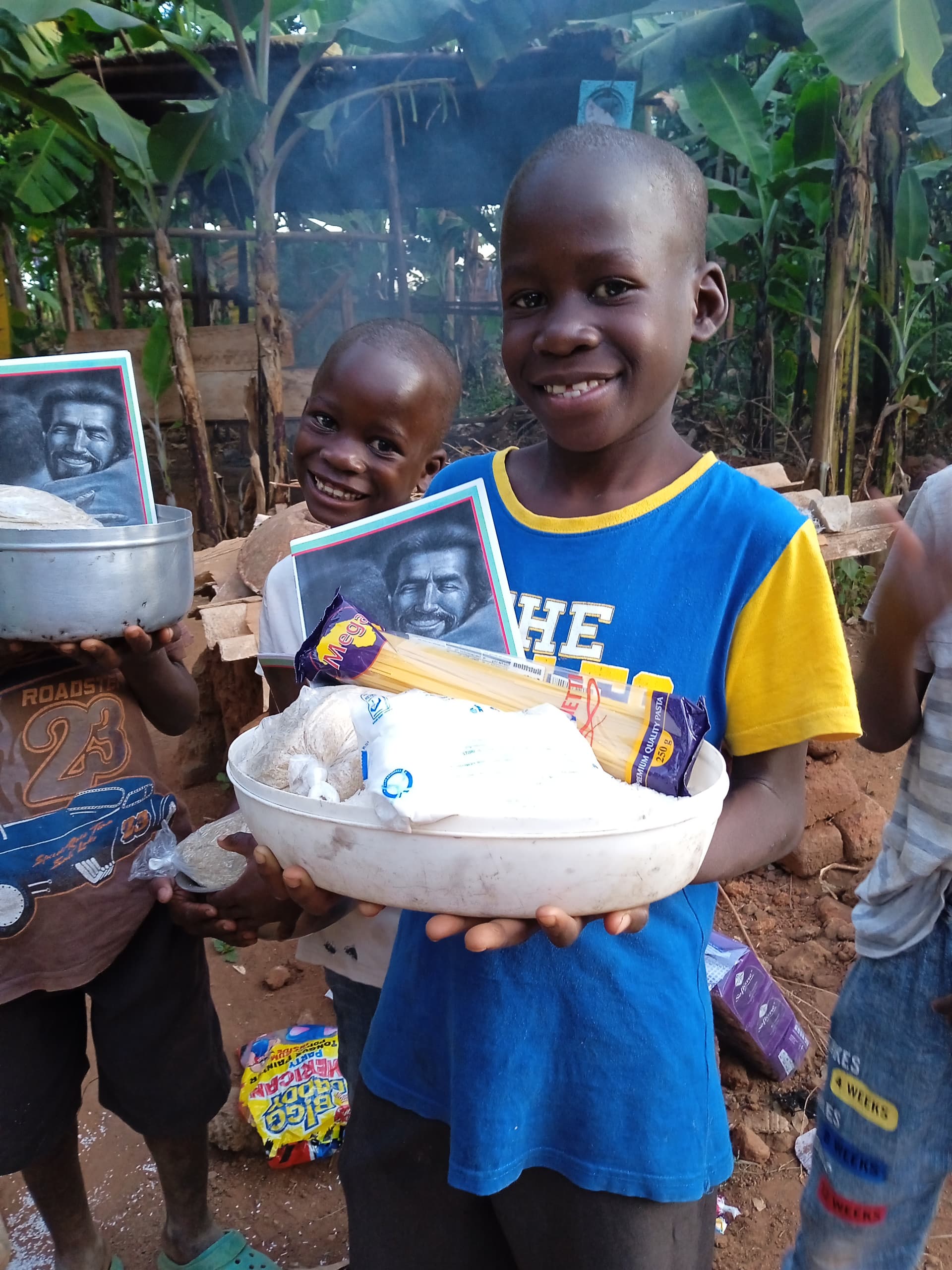 Boy in a blue and yellow shirt holds a white bowl of rice and a photo booklet.