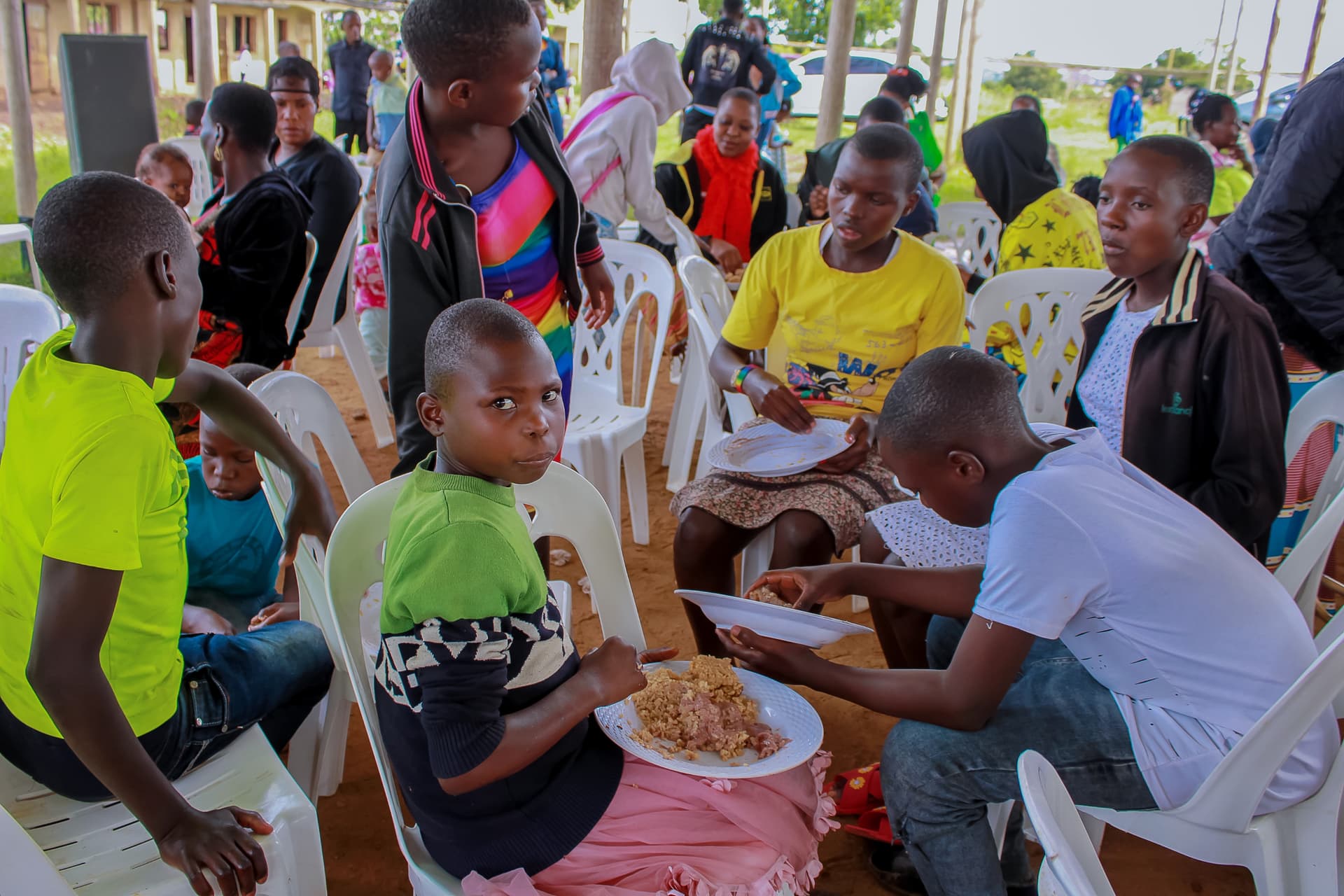 Congregation members seated in chairs eating plates of rice at a Greater Works Ministries church event.