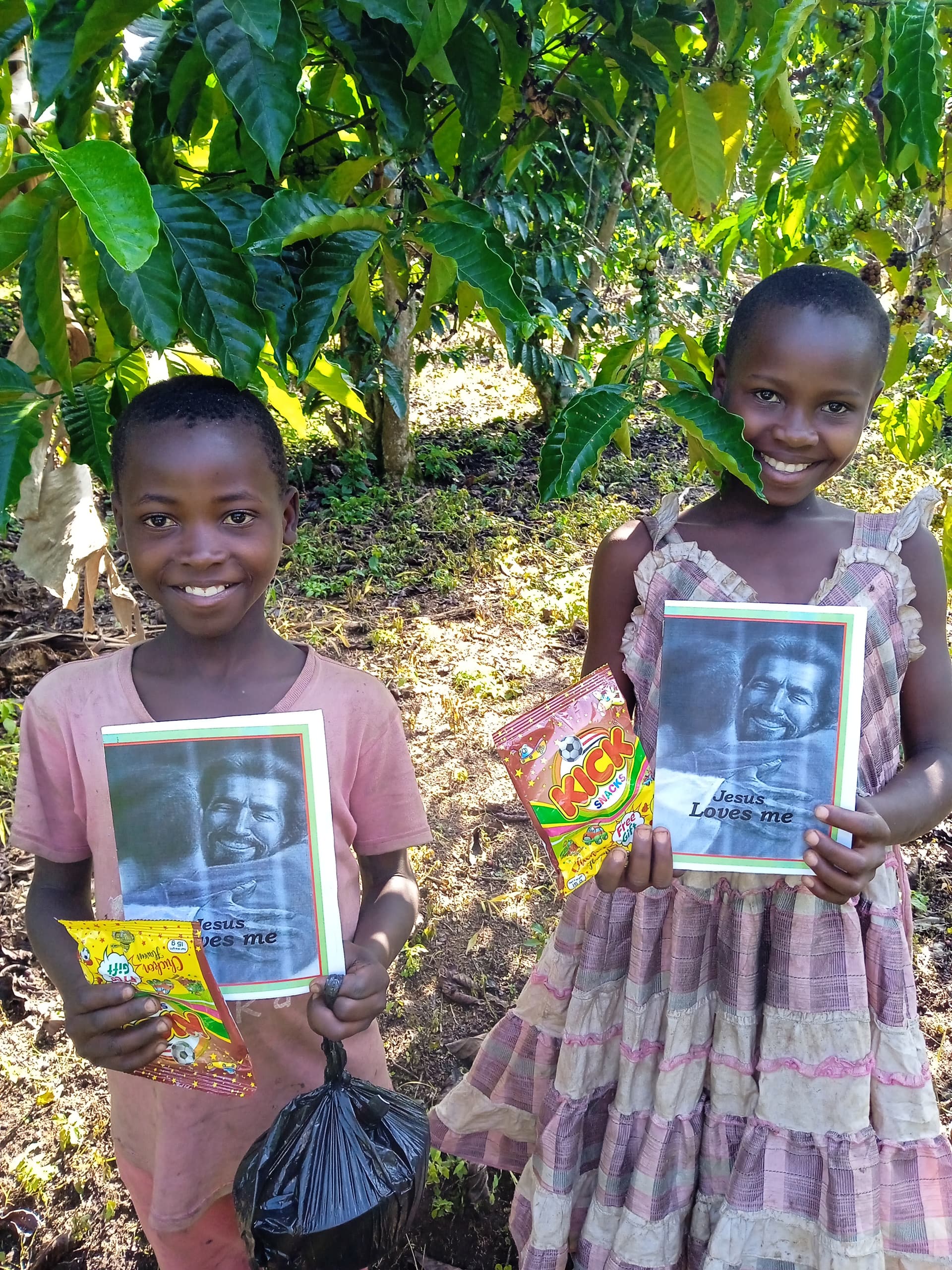 Two girls standing outdoors, smiling and holding a photo card and a packaged snack.