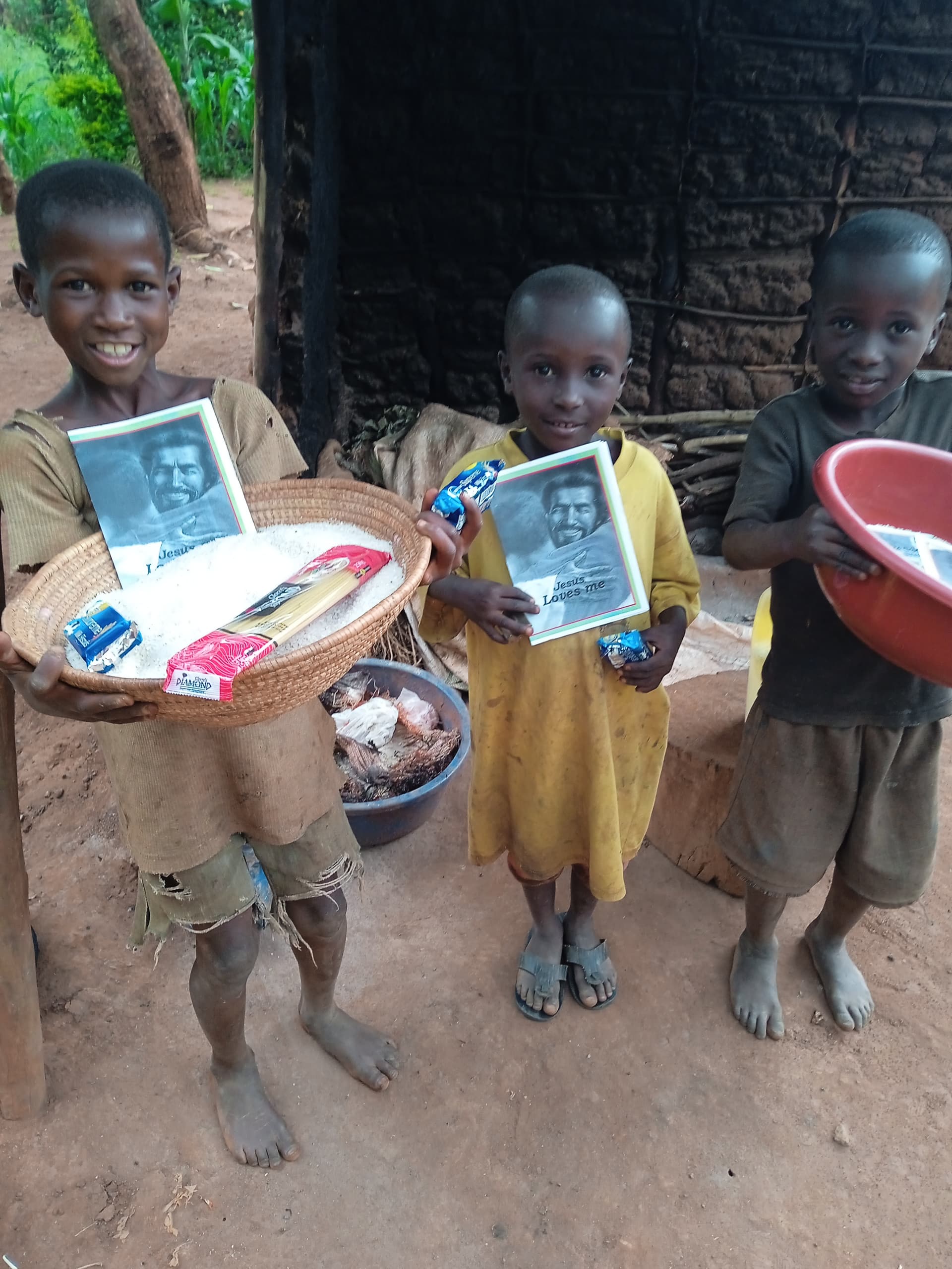 Two children standing outdoors each holding trays of food and a photo card, one with a red bowl.