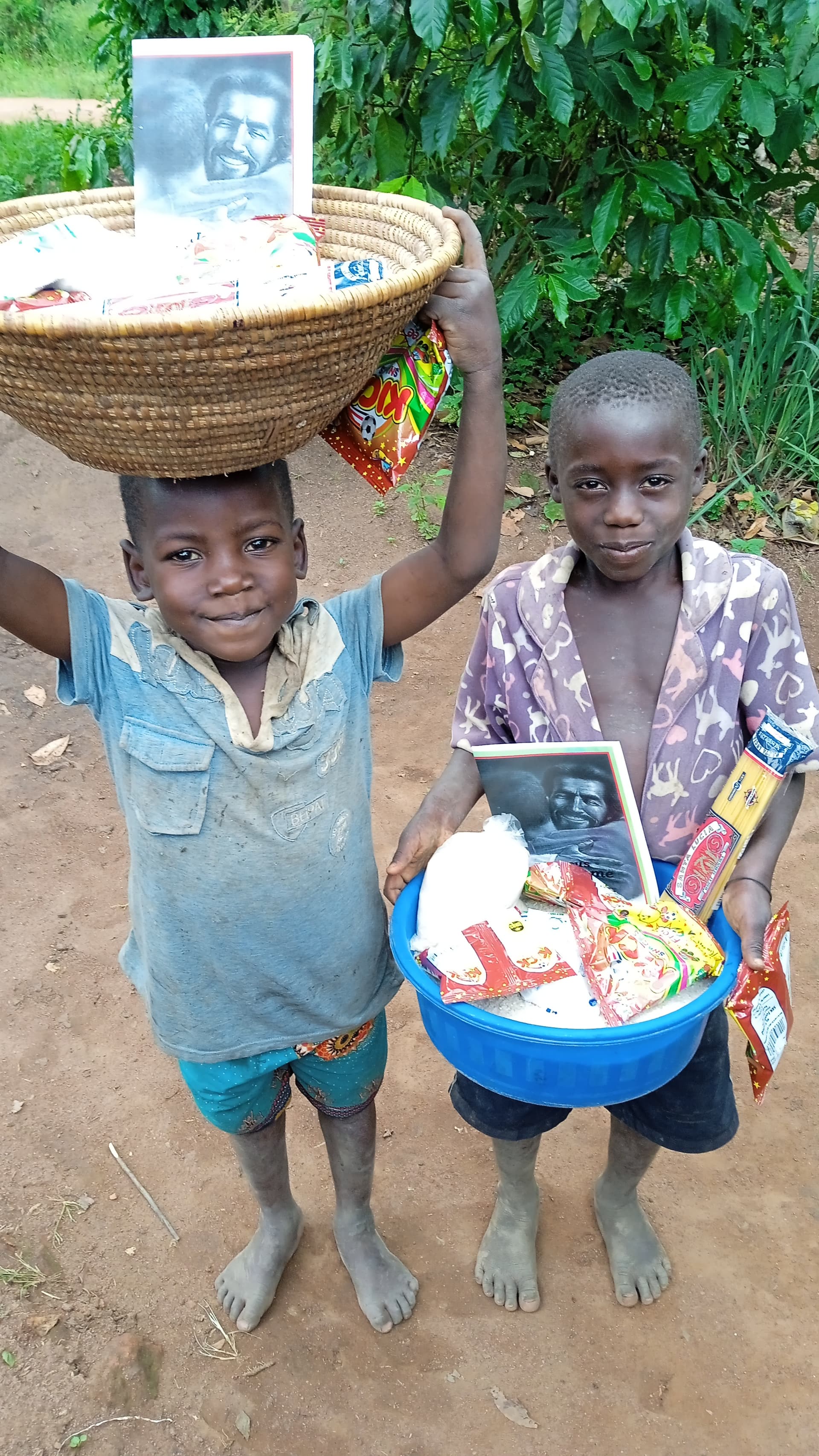 Two children carry a basket of food on their heads while holding a JFM photo card.