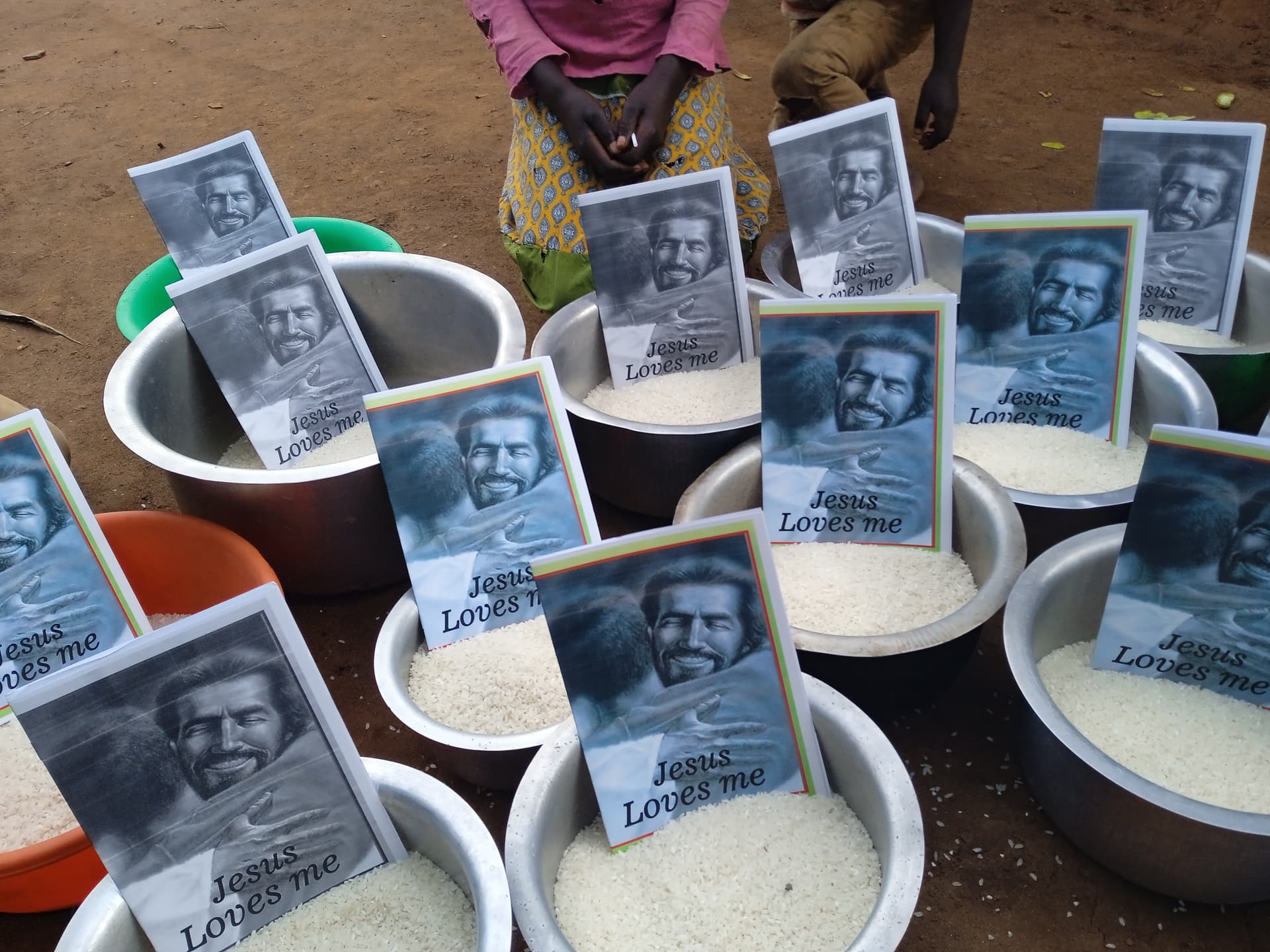 Bowls of maize flour arranged for distribution, each topped with a gospel tract booklet.