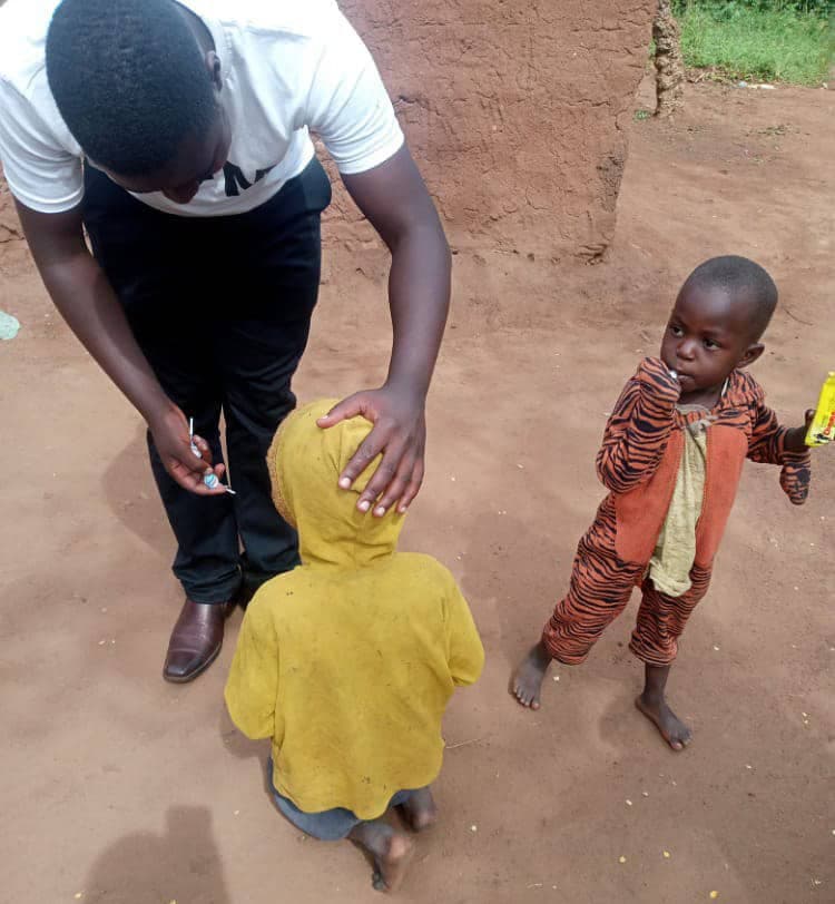 A man in a white shirt places his hand on a child's head in blessing as another child stands nearby.