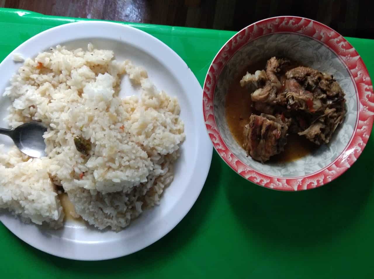 A plate of rice and a bowl of meat stew served on a green table for the children's meal.