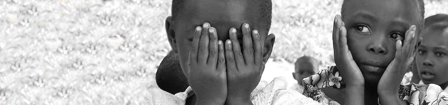 Black-and-white close-up of children covering their faces with their hands.