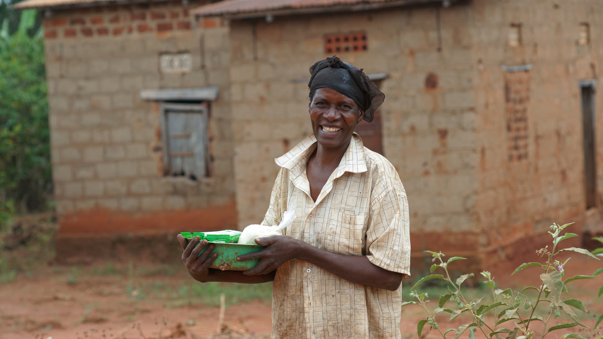 Woman stands outside a brick house holding a food gift box.